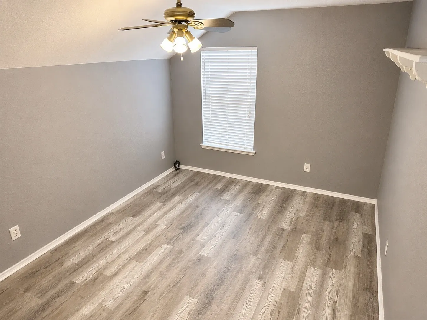 Room with wood-finish flooring, neutral gray walls, and white baseboards