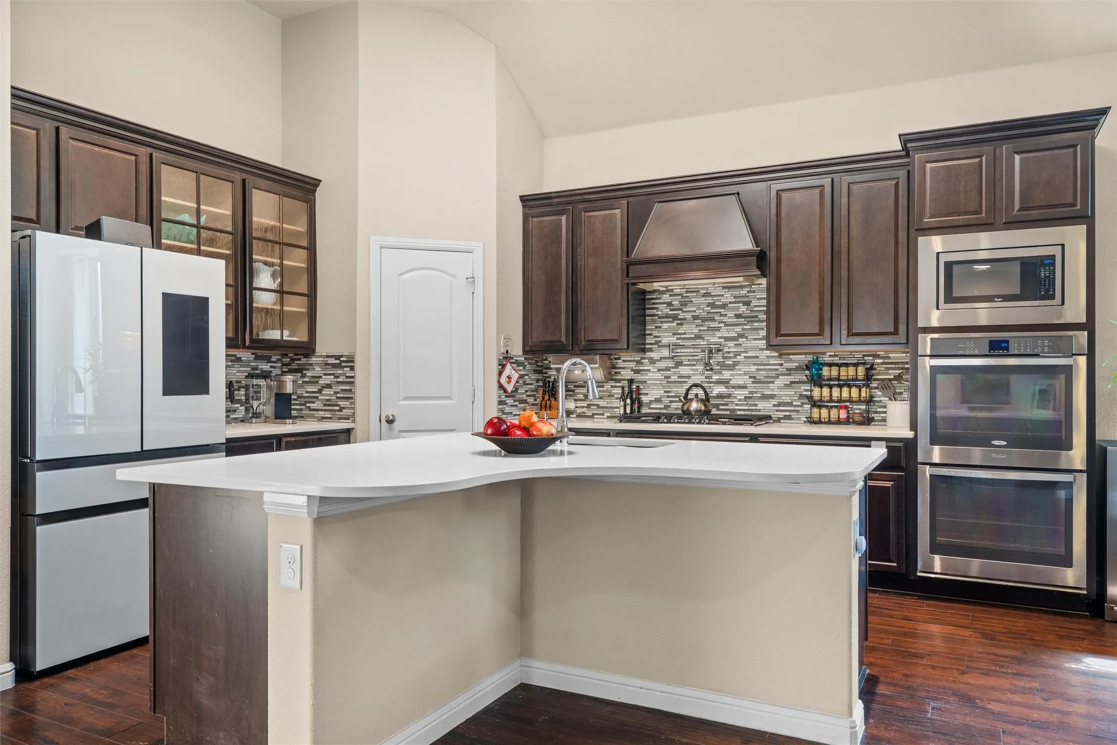 The gourmet kitchen is outfitted with quartz countertops, custom cabinetry, glass-front cabinets, double ovens, oversized island, gas cooktop, pot filler, and walk-in pantry.
