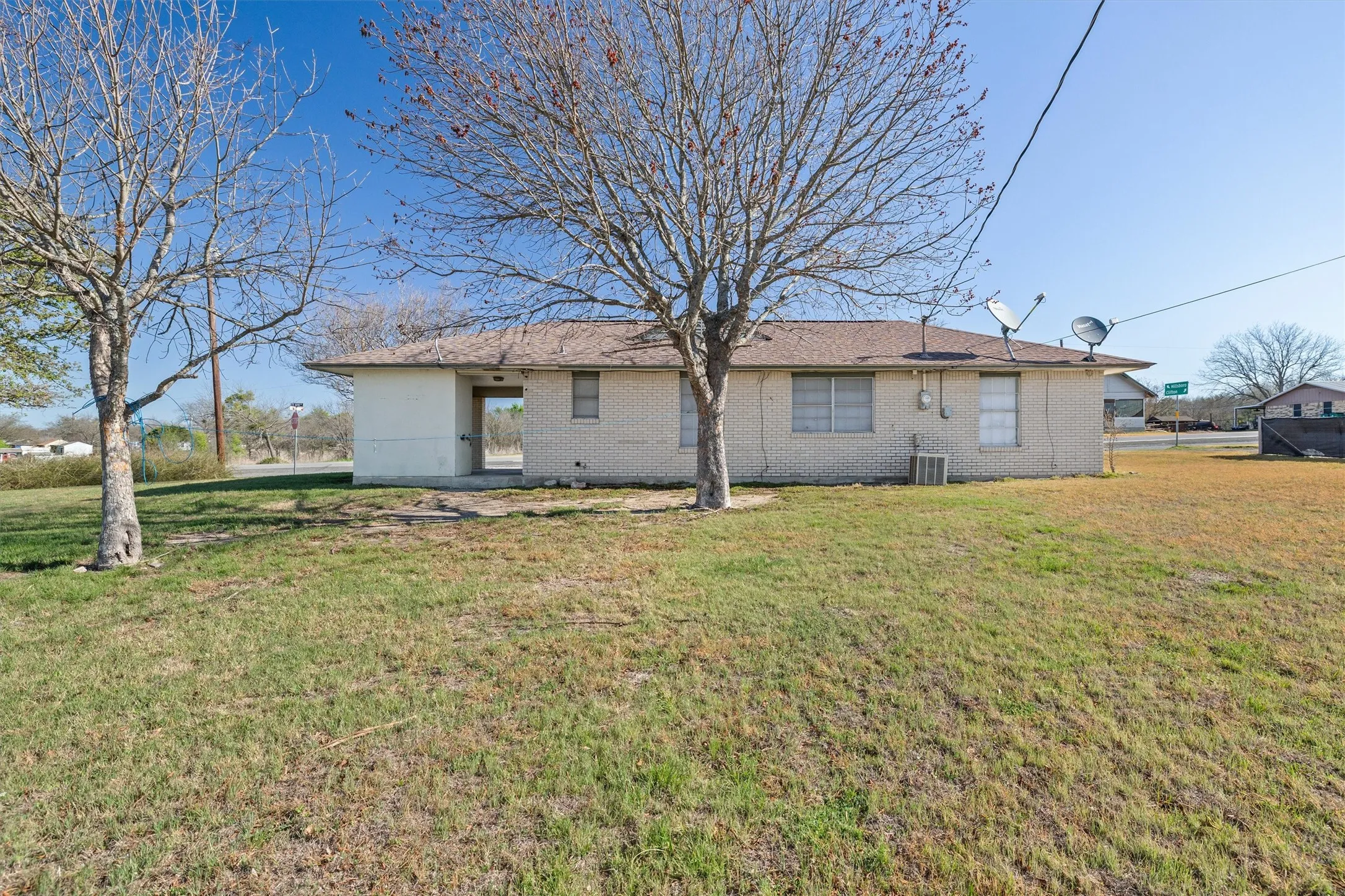 Back of house with brick siding and a lawn