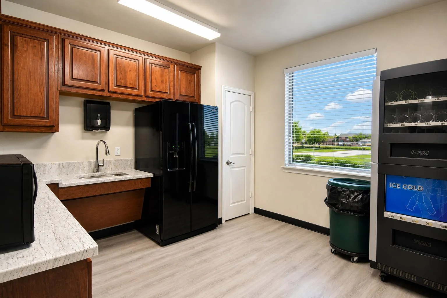 Kitchenette featuring wood-finish cabinetry, light-toned countertops, and light wood-finish flooring