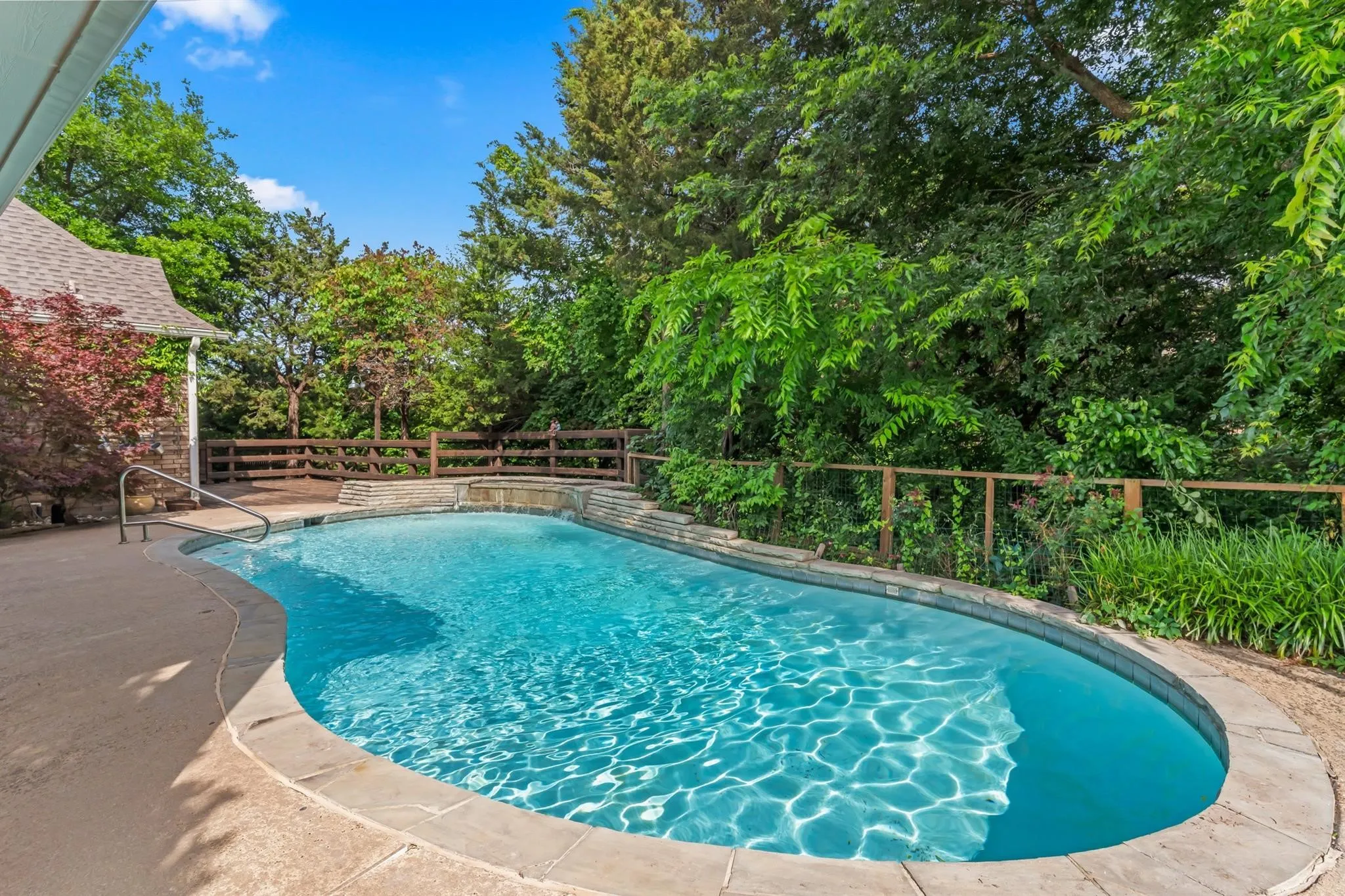 View of swimming pool featuring a fenced backyard, patio surround, and view of wooded area