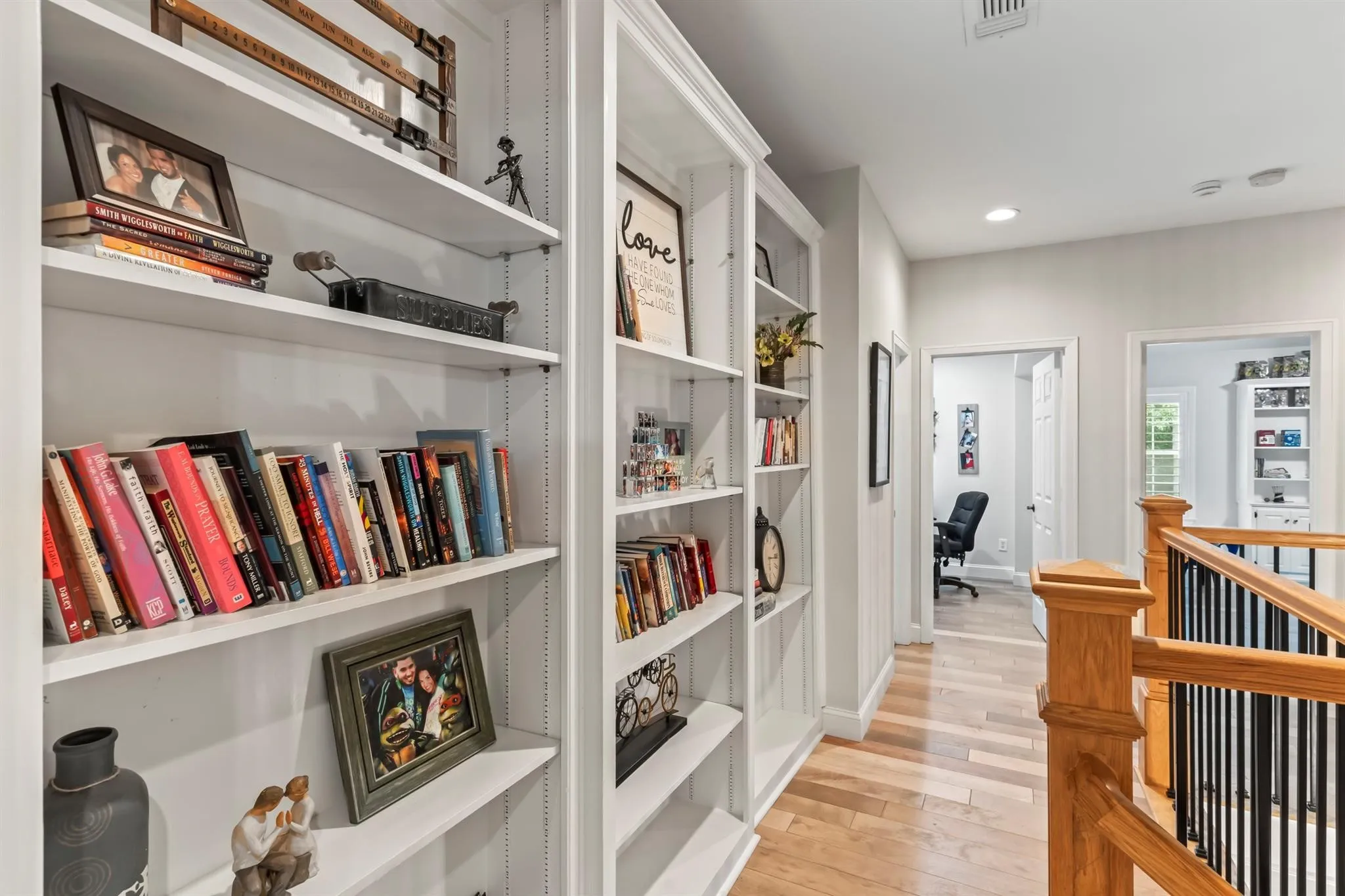 Hallway with light wood-type flooring, an upstairs landing, built in features, a desk, and recessed lighting