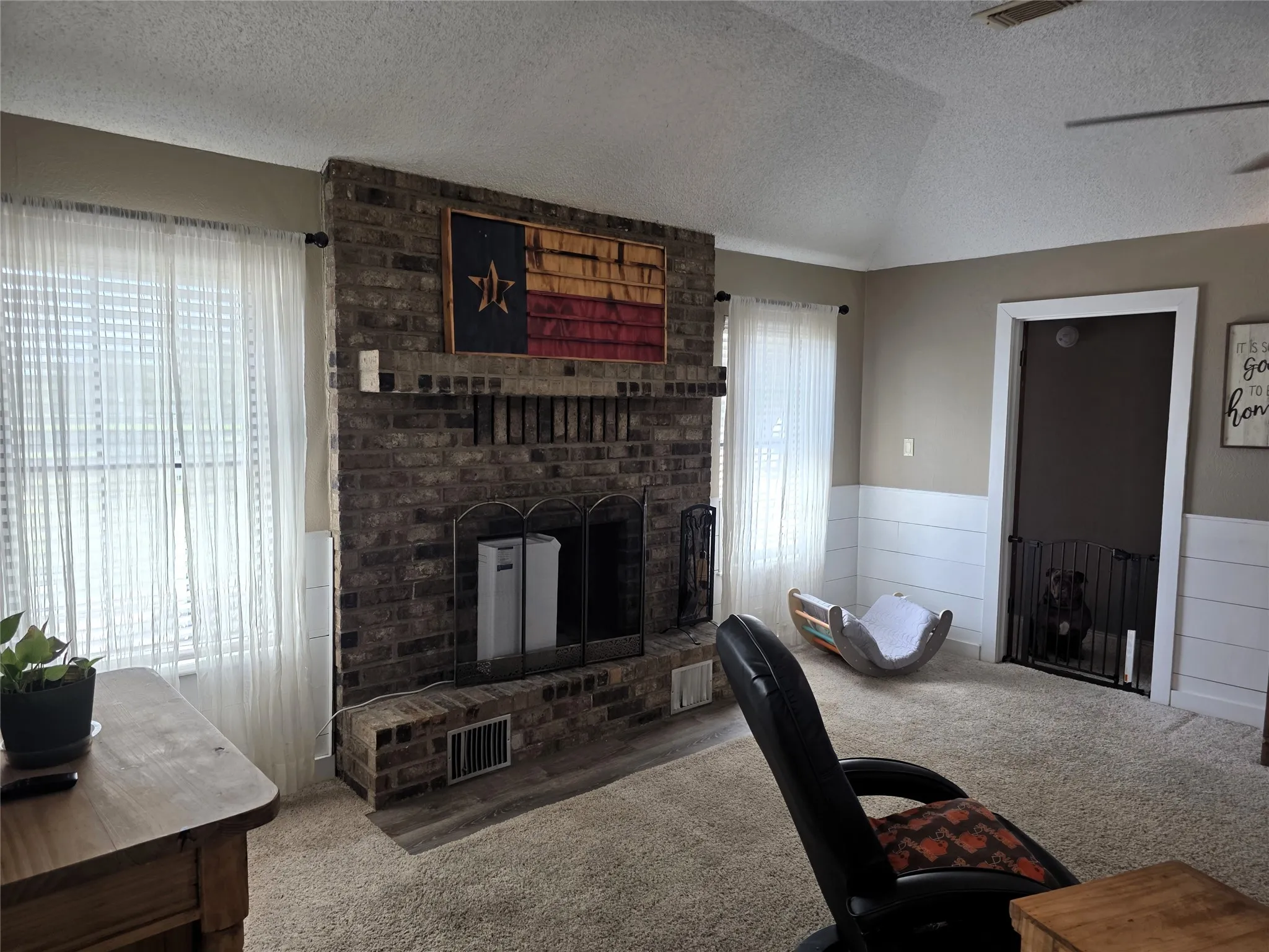 Living room featuring carpet floors, a brick fireplace, and wainscoting