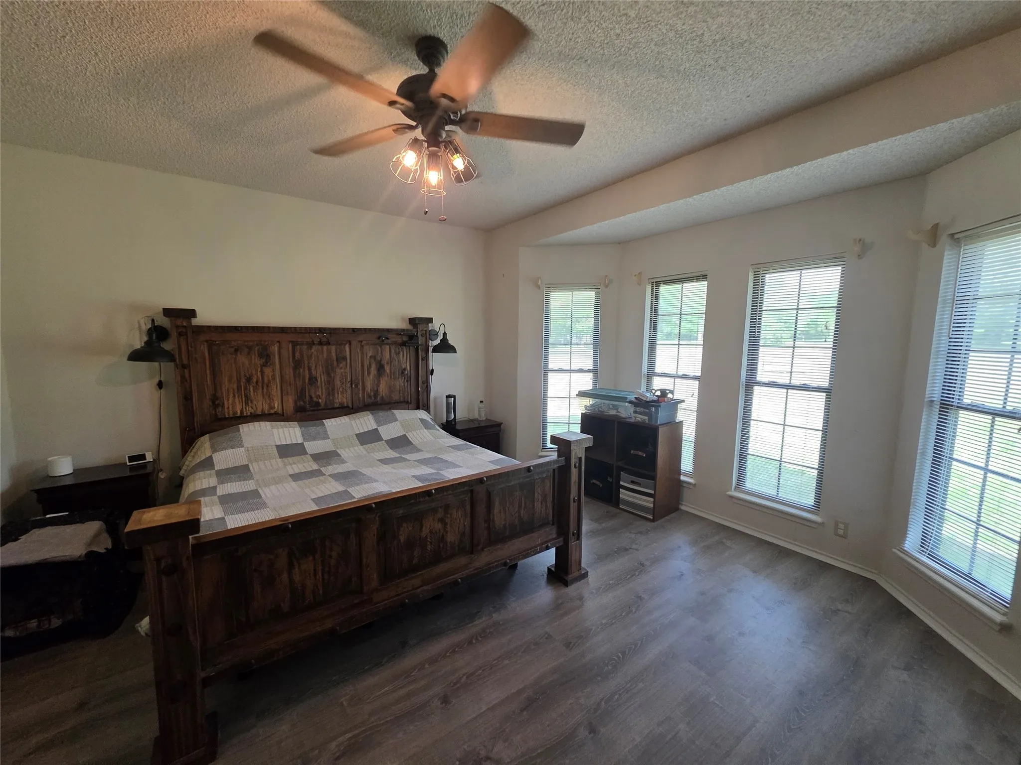 Bedroom with dark wood-style flooring, a textured ceiling, and a ceiling fan