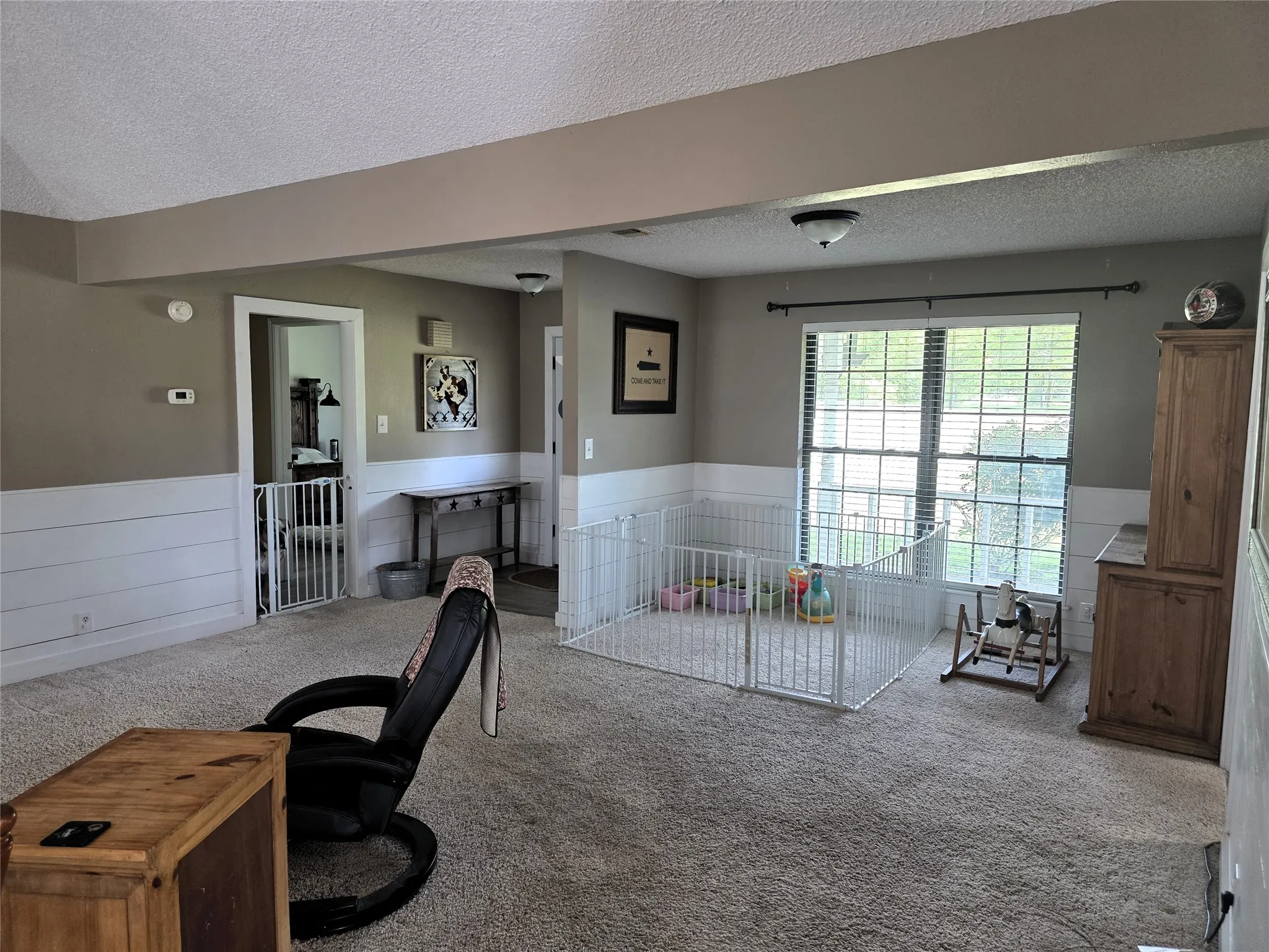 Carpeted office featuring wainscoting and a textured ceiling