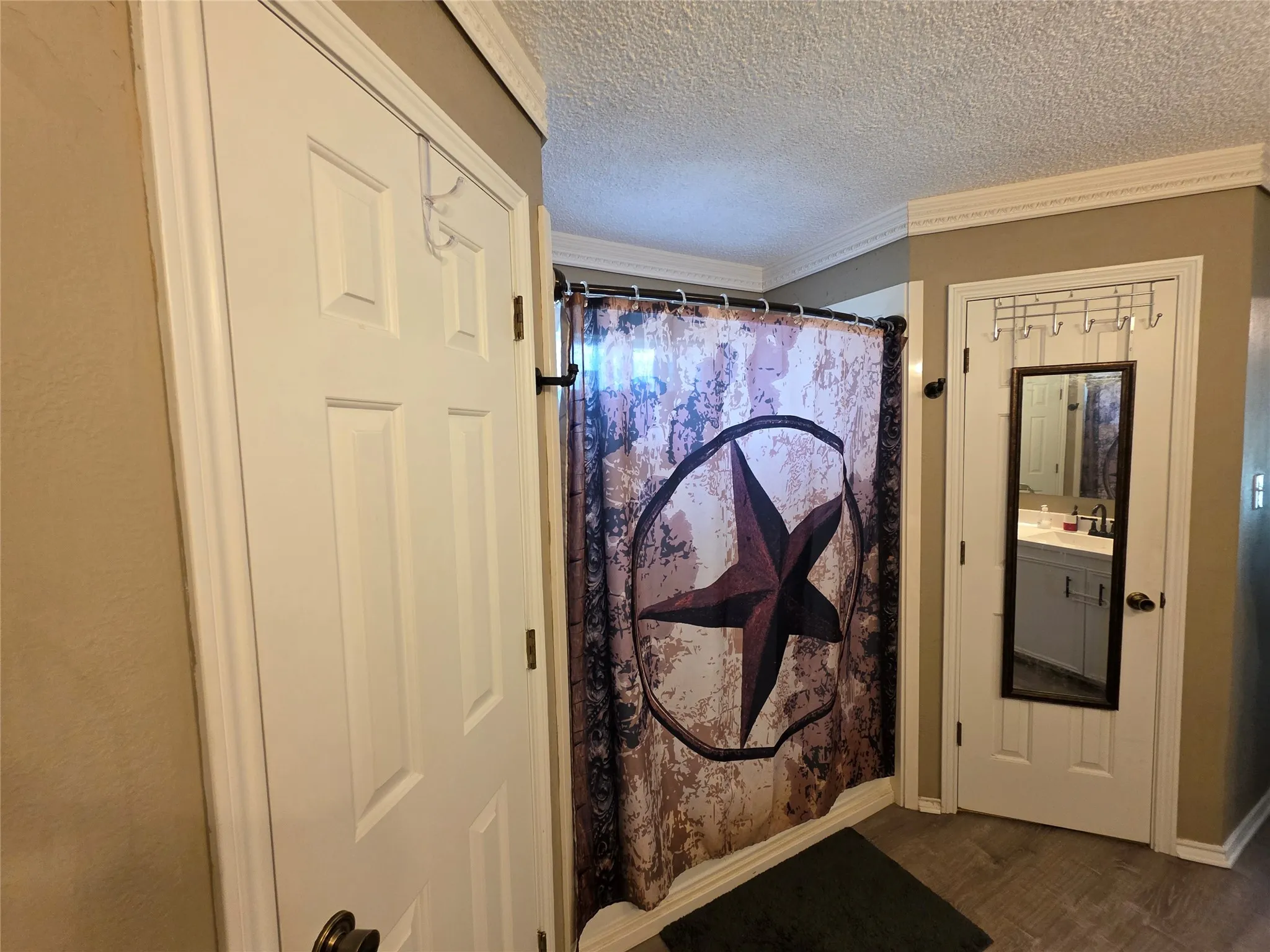 Bathroom with a shower with curtain, ornamental molding, a textured ceiling, and dark wood finished floors