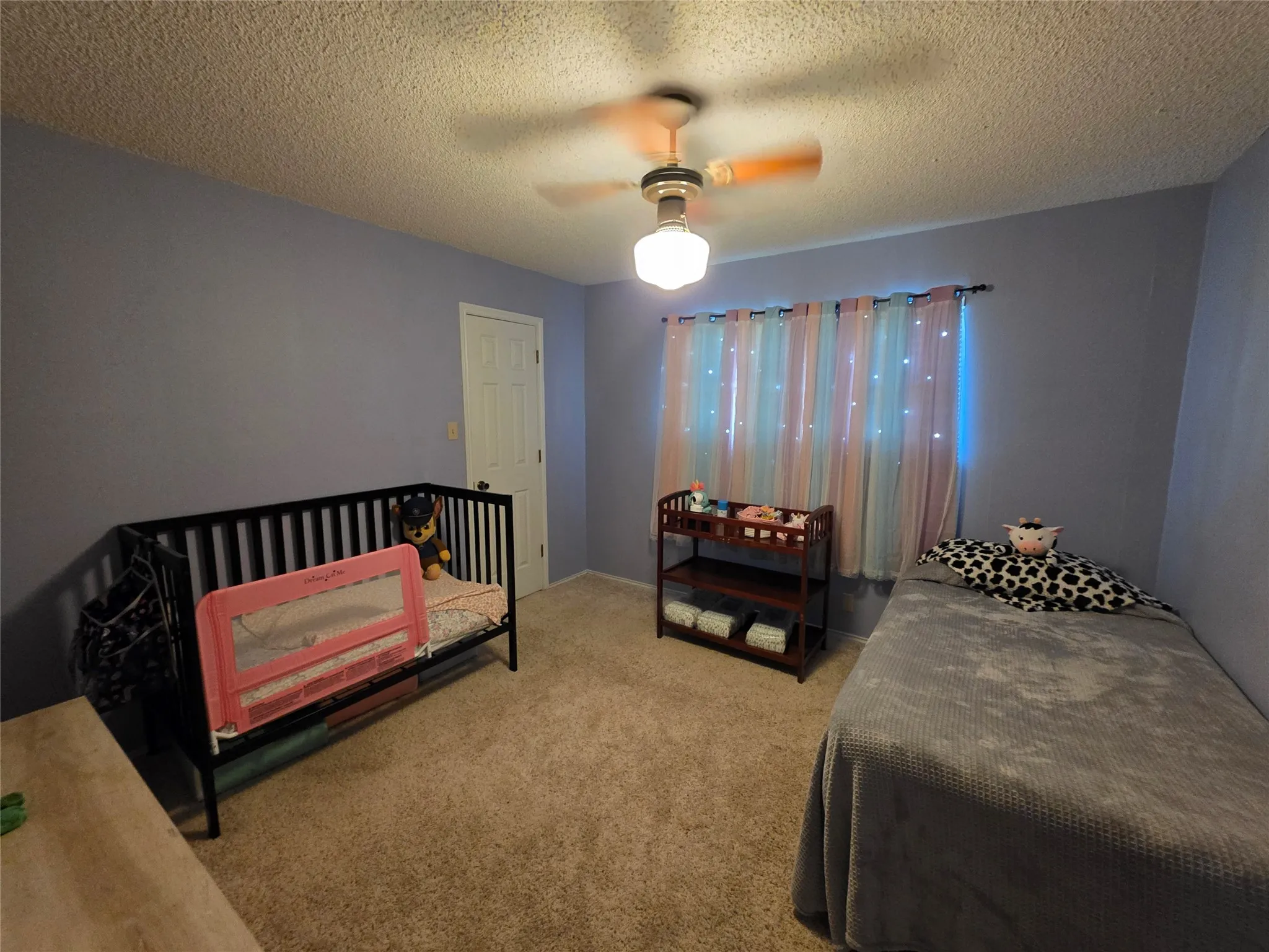 Carpeted bedroom with a textured ceiling and a ceiling fan