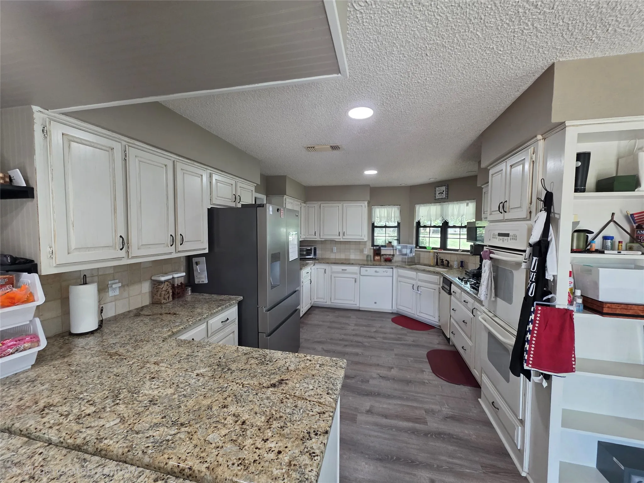 Kitchen with white cabinetry, a textured ceiling, white appliances, backsplash, and dark wood-type flooring