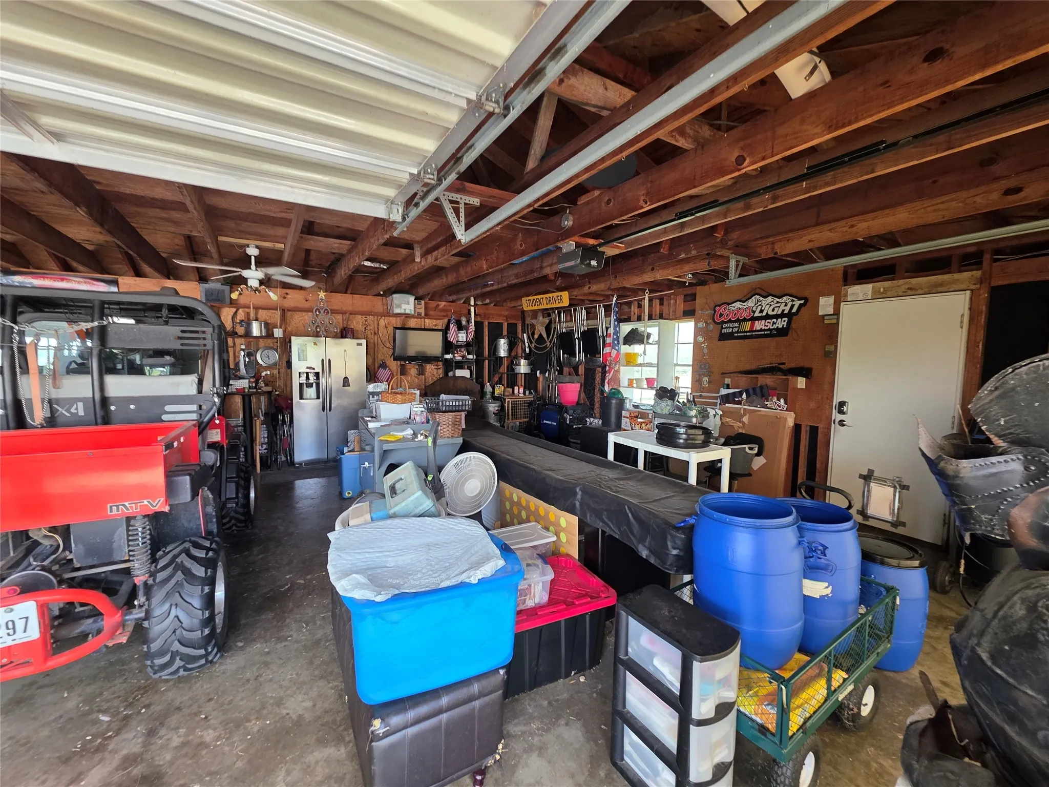 Garage featuring stainless steel refrigerator with ice dispenser and a garage door opener