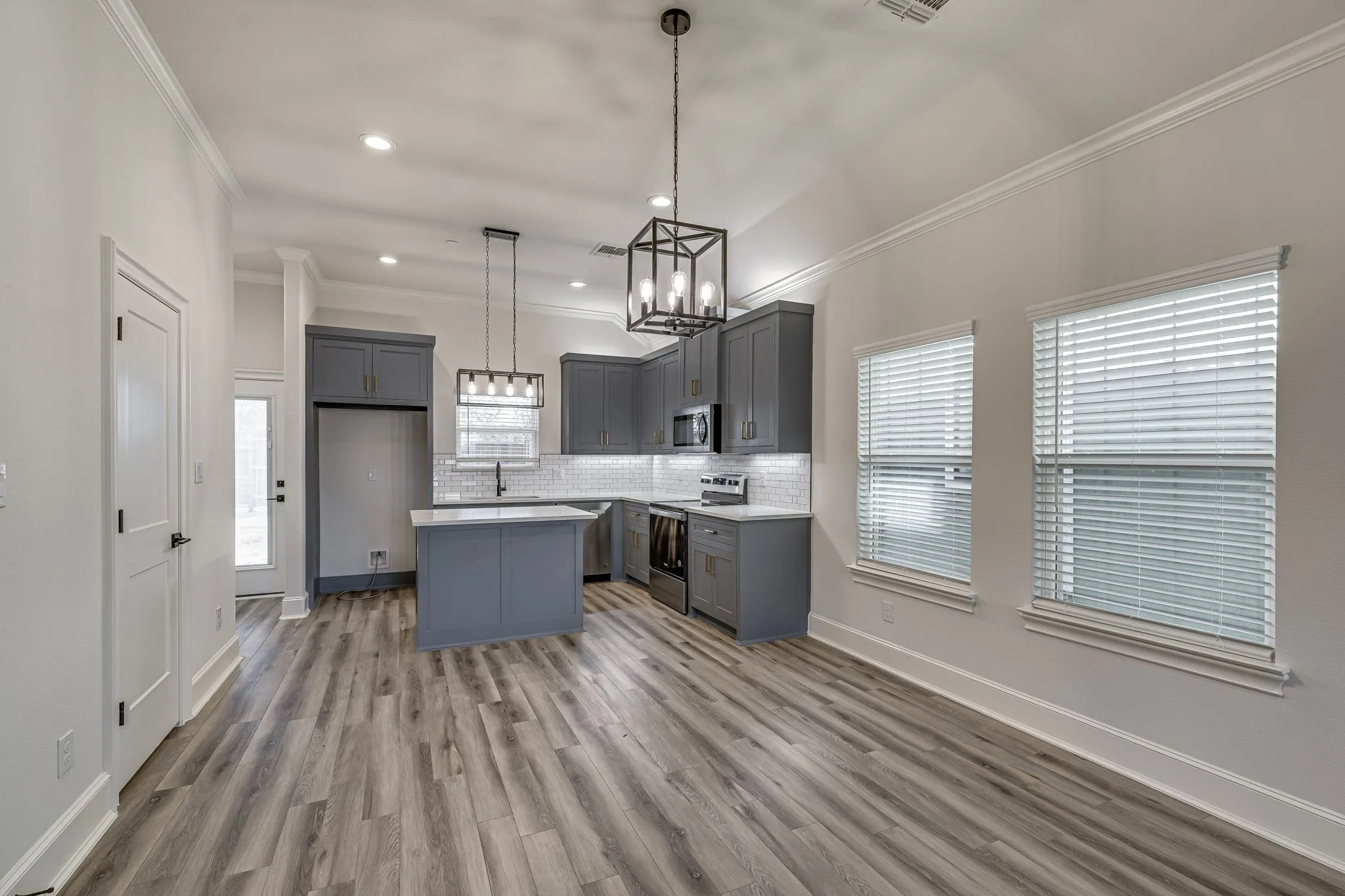 Kitchen featuring a center island, gray cabinets, stainless steel appliances, ornamental molding, and decorative backsplash