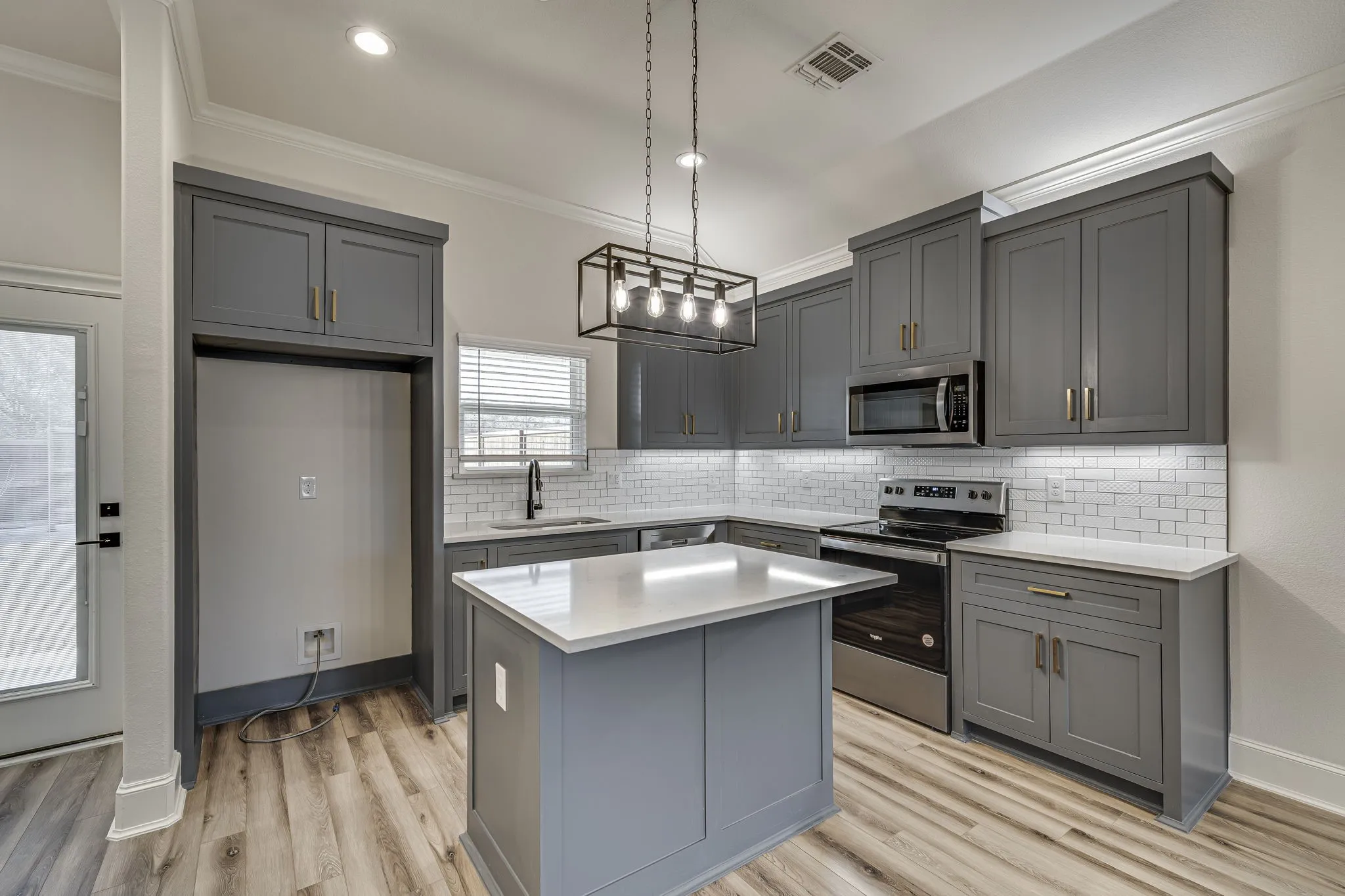 Kitchen featuring stainless steel appliances, gray cabinets, a kitchen island, and ornamental molding