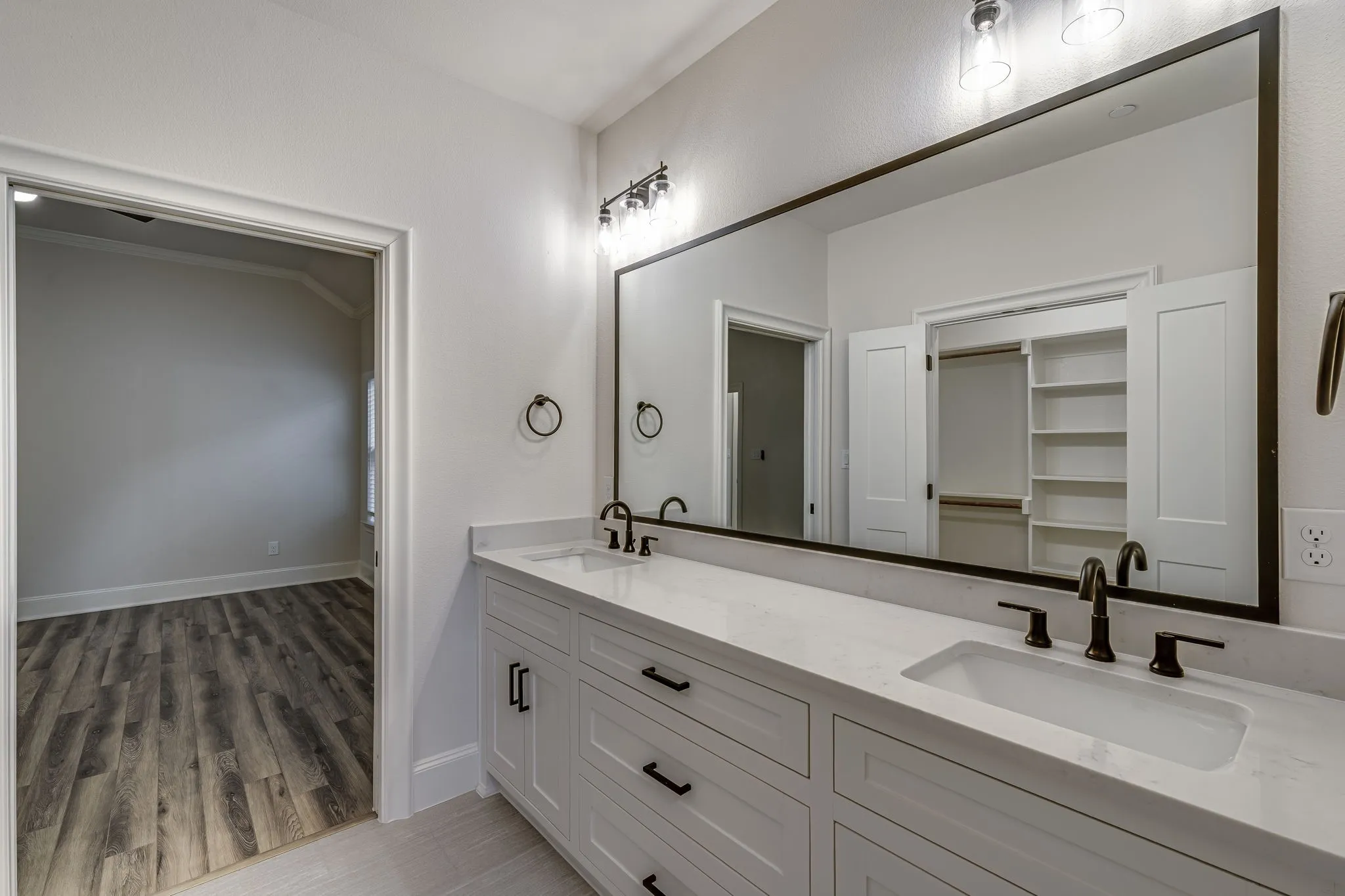 Full bathroom with double vanity, light wood-style flooring, and a walk in closet