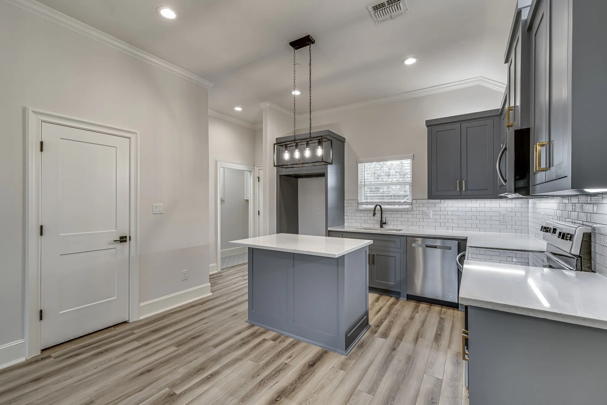 Kitchen featuring gray cabinetry, a kitchen island, stainless steel appliances, light wood-type flooring, and backsplash