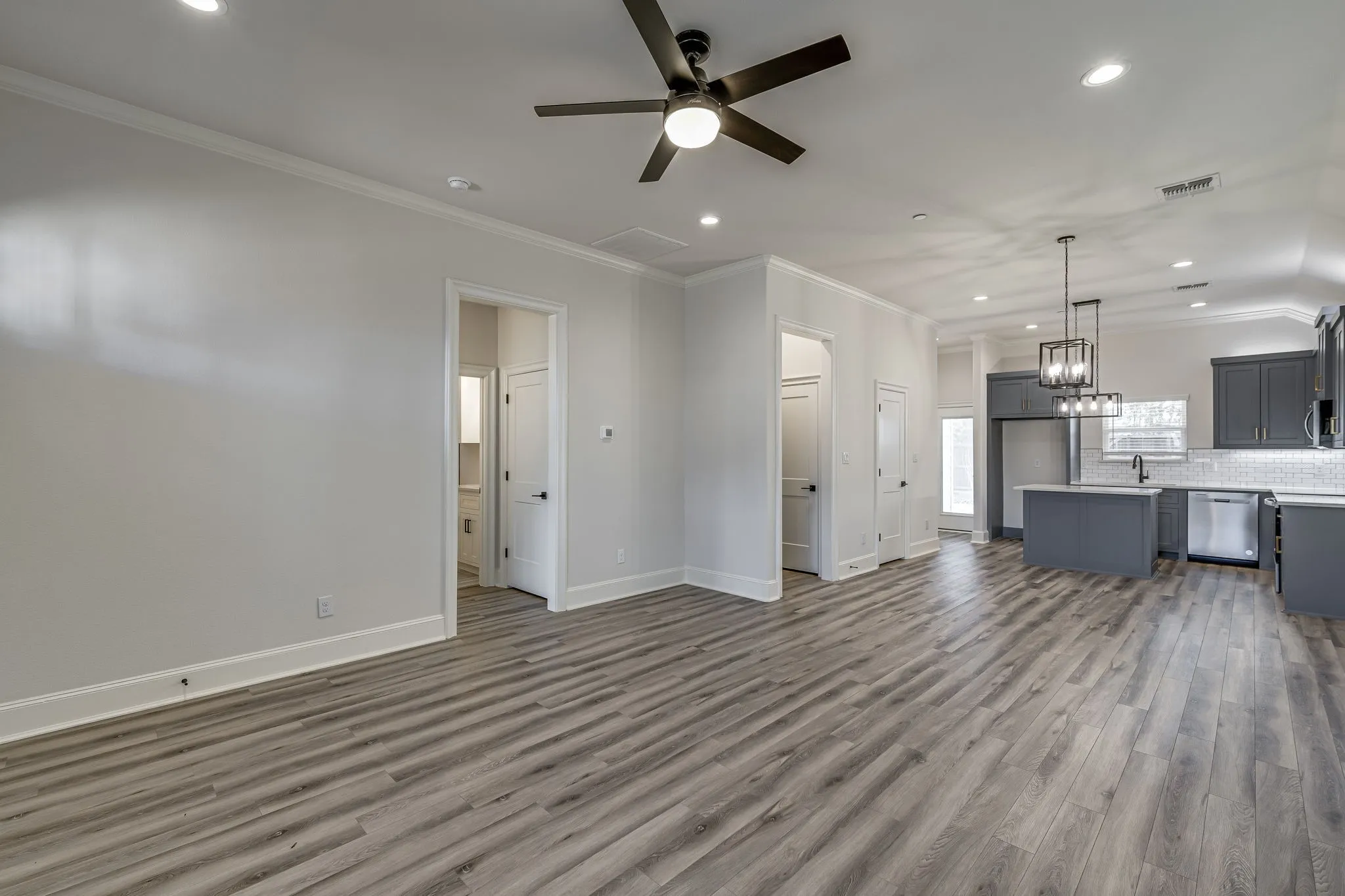 Unfurnished living room with crown molding, a ceiling fan, dark wood-type flooring, and a chandelier