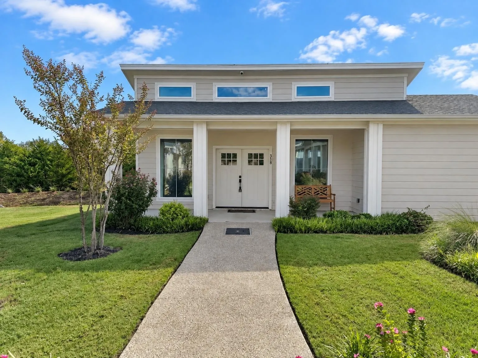 Modern architectural design featuring a prominent entryway, a gabled roofline, and transom windows