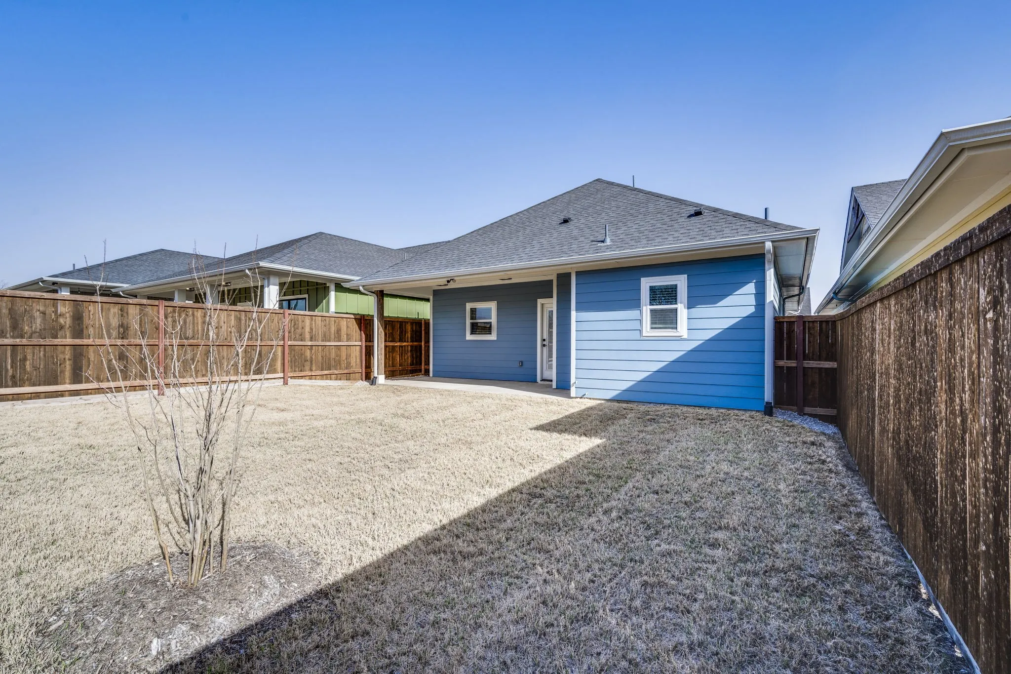 Rear view of house with a patio, a shingled roof, and a fenced backyard