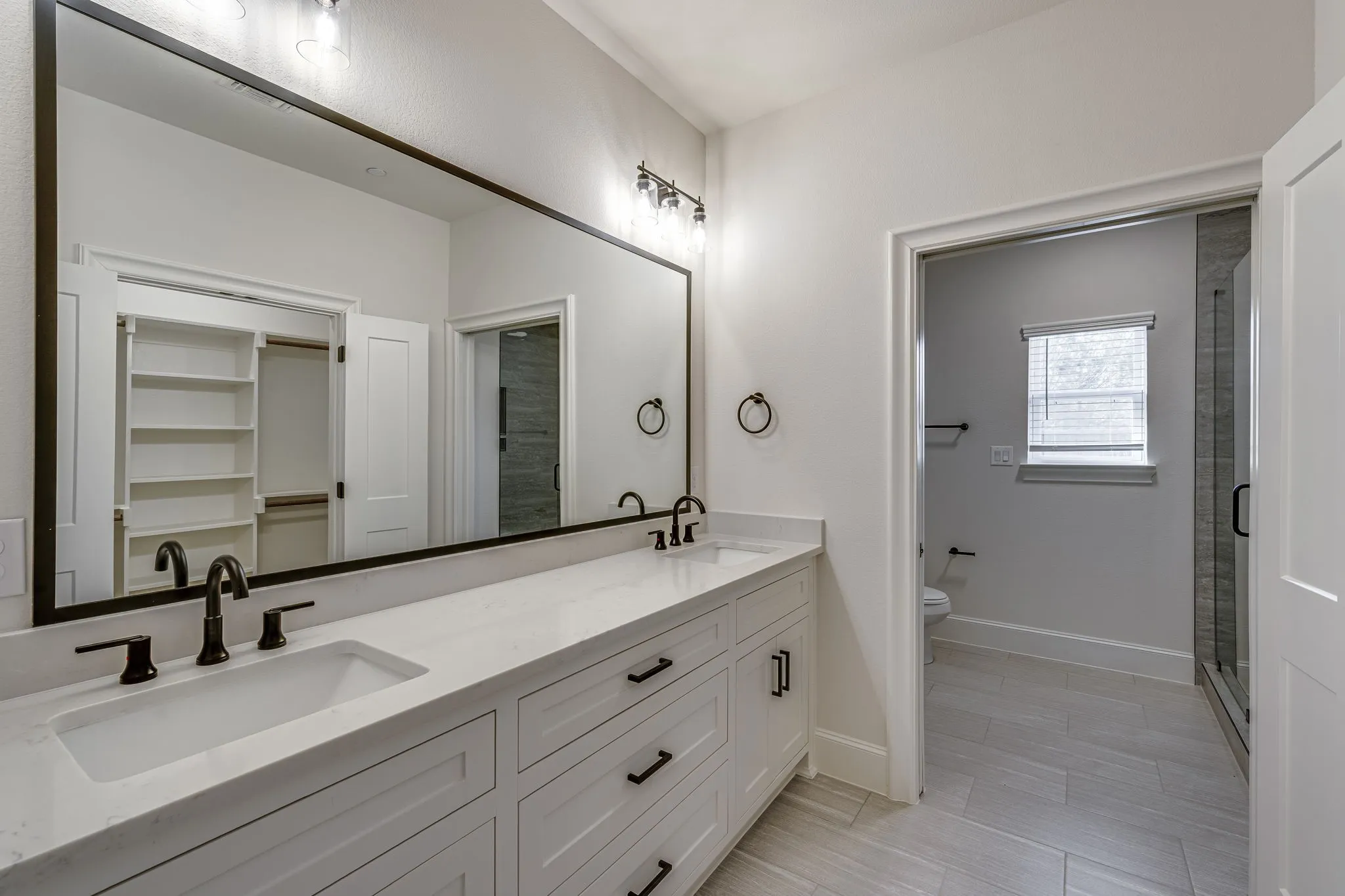 Bathroom with double vanity, a shower stall, and a spacious closet