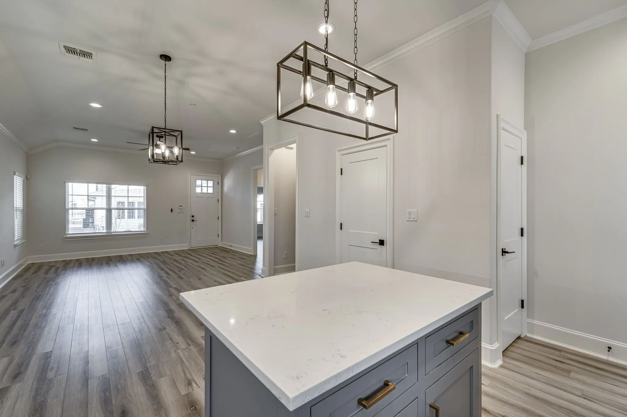 Kitchen with ornamental molding, gray cabinetry, a center island, dark wood-style flooring, and light stone countertops