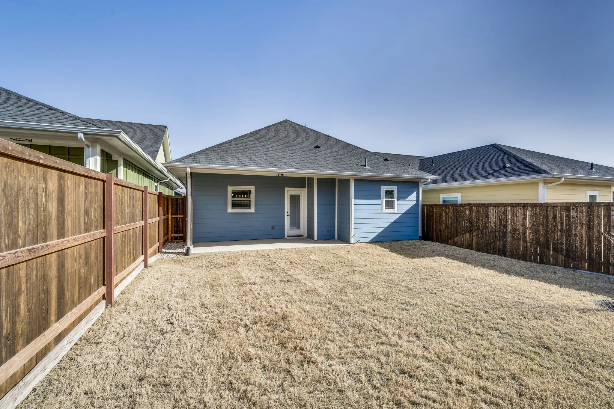 Back of house with a patio, roof with shingles, and a fenced backyard