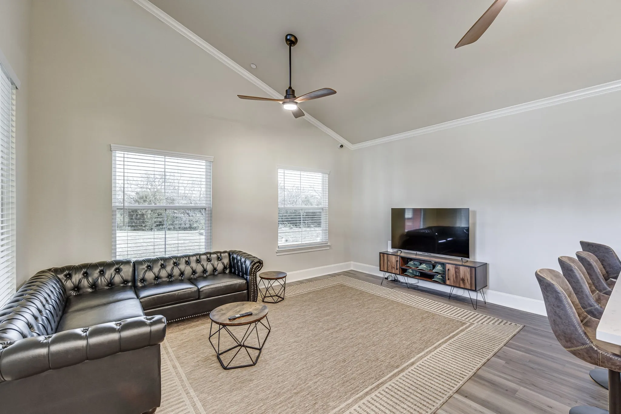 Living room with vaulted ceiling, a ceiling fan, wood finished floors, and ornamental molding