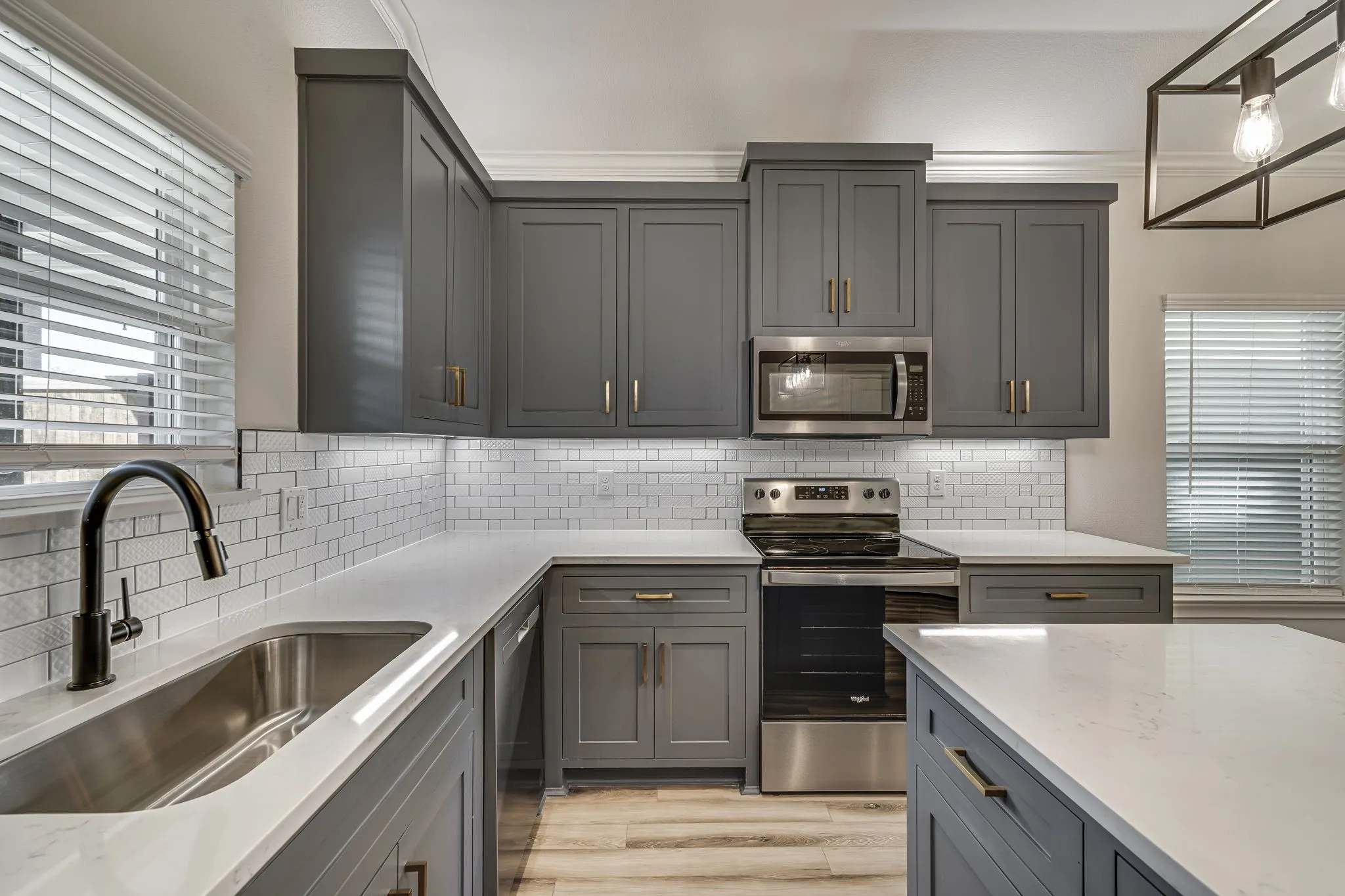 Kitchen featuring gray cabinetry, stainless steel appliances, light stone counters, and light wood-type flooring