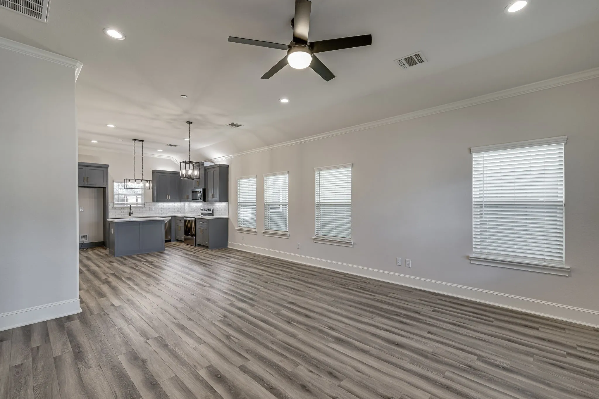 Unfurnished living room with recessed lighting, crown molding, ceiling fan, dark wood-type flooring, and healthy amount of natural light