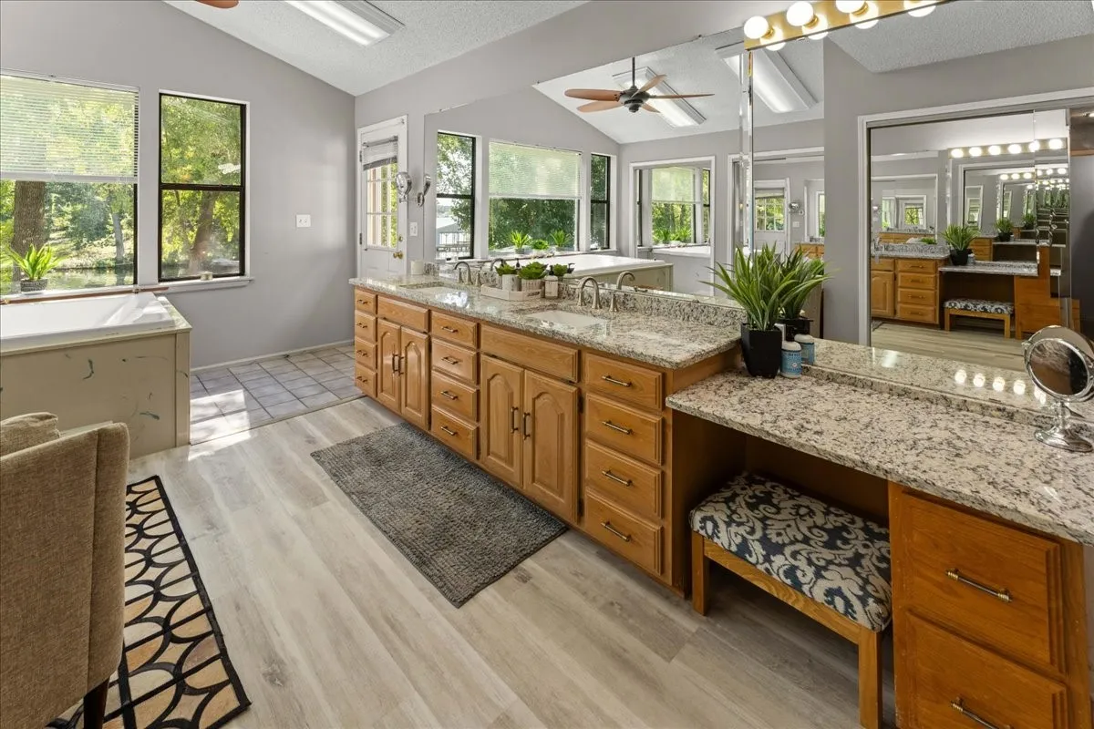 Full bath featuring lofted ceiling, ceiling fan, a textured ceiling, double vanity, and light wood finished floors