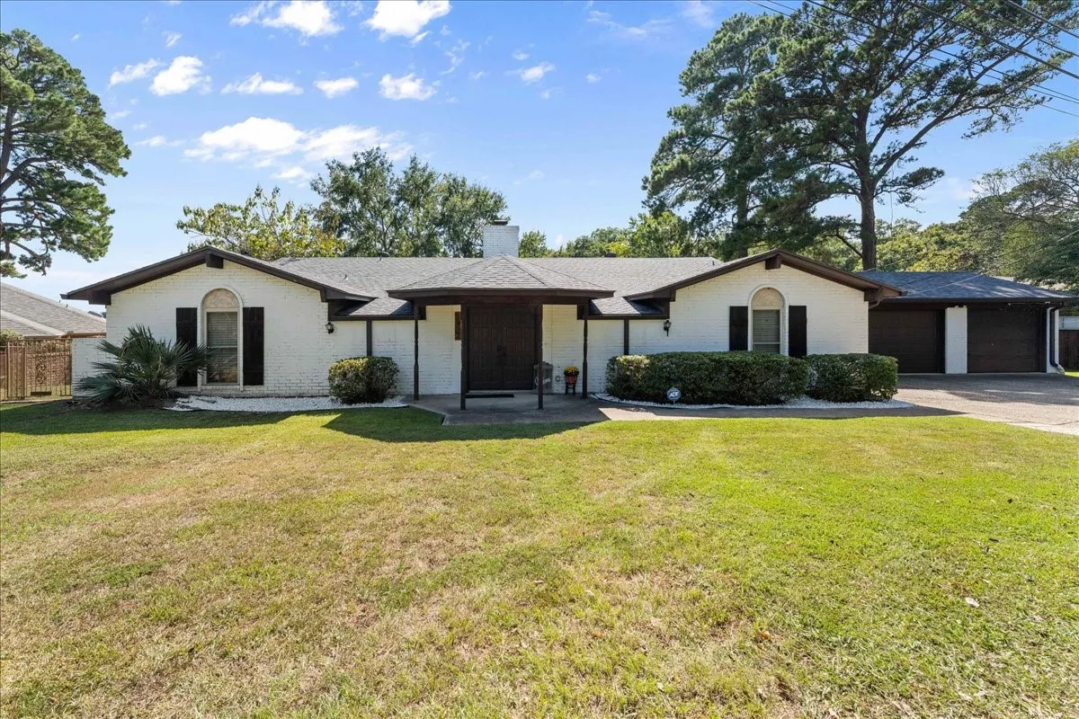 Single story home with a front lawn, a chimney, brick siding, and a garage