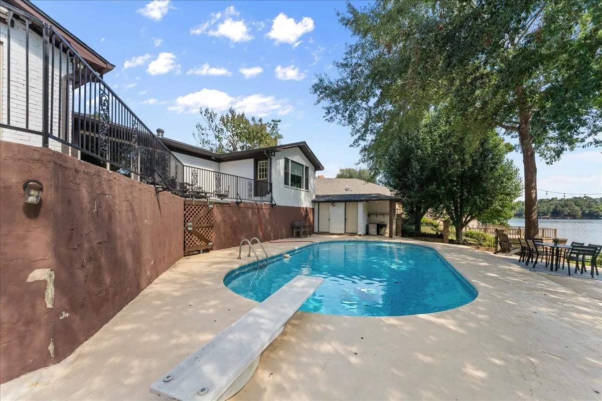View of pool with a diving board, a patio area, and a water view