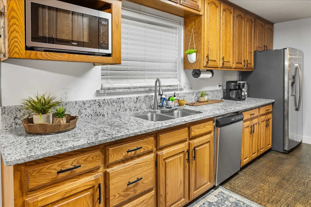 Kitchen with stainless steel appliances, light stone counters, and brown cabinets