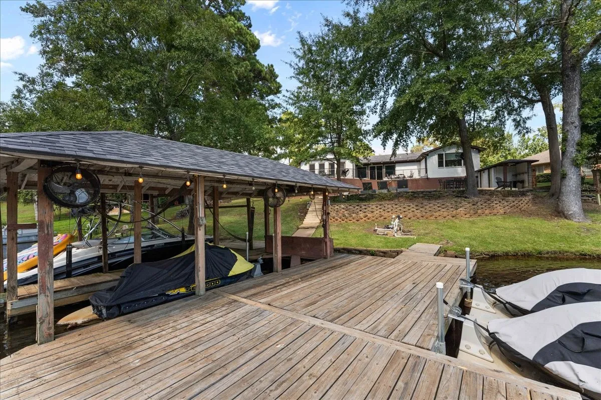 Dock area with boat lift, a water view, and a yard