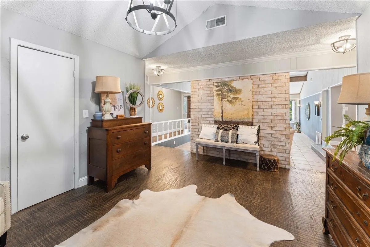 Living area with a textured ceiling, vaulted ceiling, and a chandelier