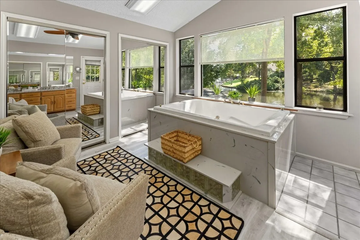 Bathroom with lofted ceiling, vanity, a whirlpool tub, light wood finished floors, and a ceiling fan