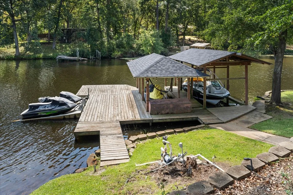 Dock area with a water view, boat lift, and view of scattered trees