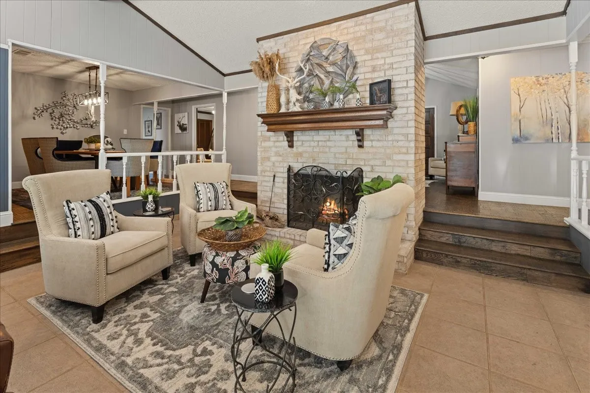 Living room featuring lofted ceiling, a fireplace, light tile patterned floors, stairs, and ornamental molding
