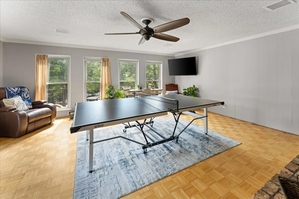 Recreation room with crown molding, a ceiling fan, and a textured ceiling
