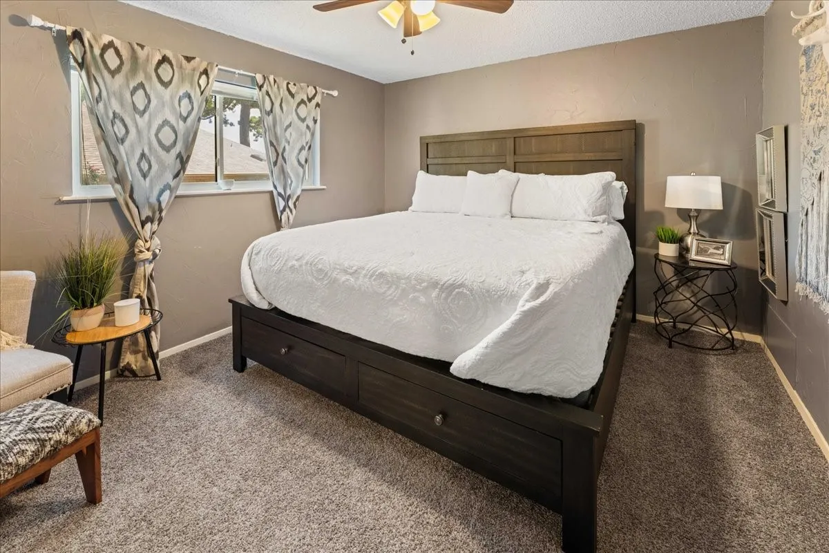 Bedroom with carpet floors, a textured ceiling, and a ceiling fan