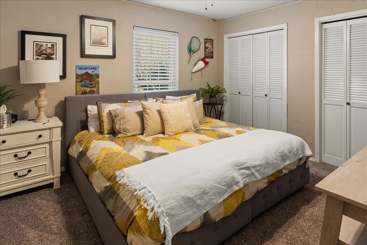 Bedroom with dark colored carpet, two closets, and a textured ceiling