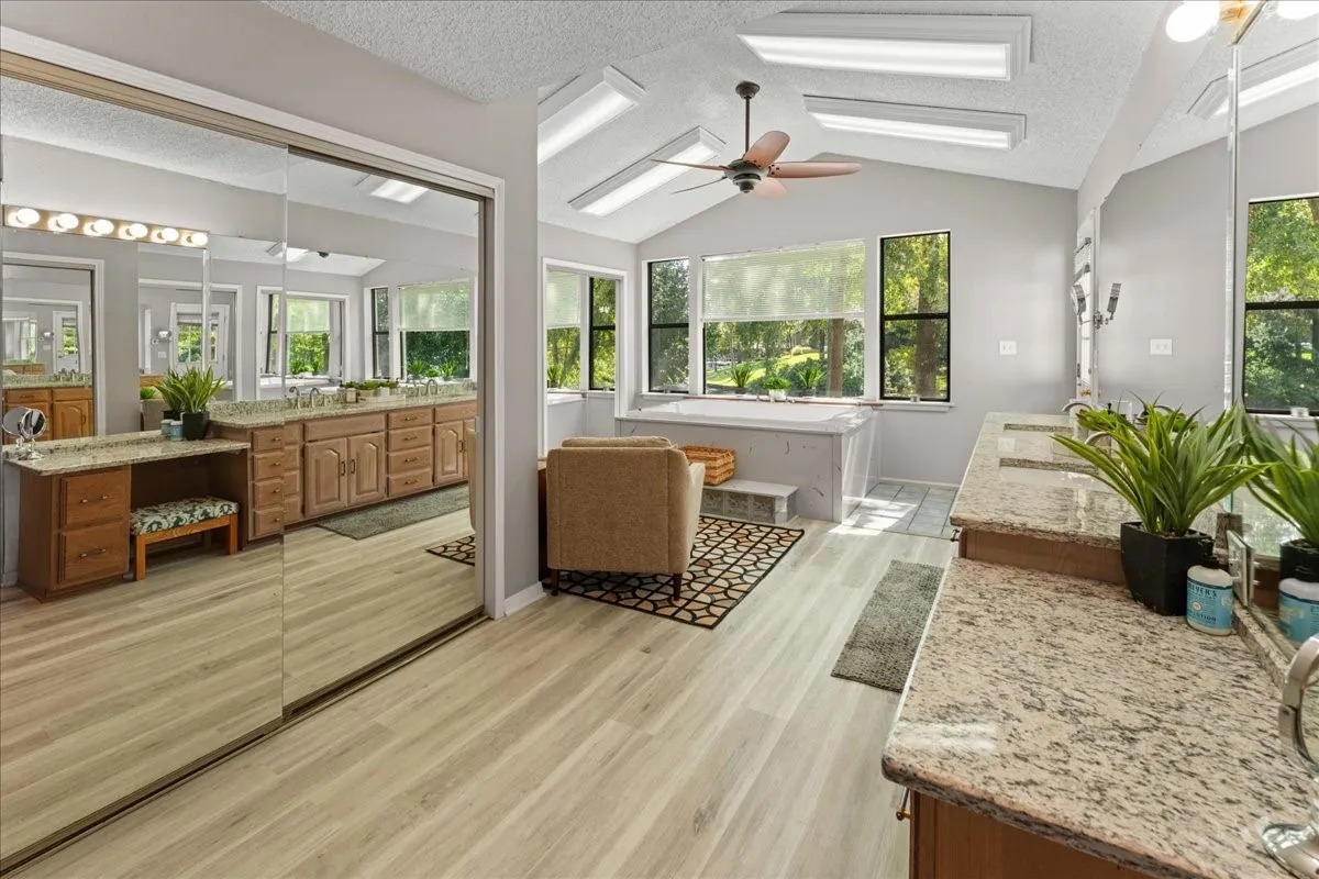 Bathroom featuring vanity, a textured ceiling, light wood-type flooring, vaulted ceiling, and plenty of natural light
