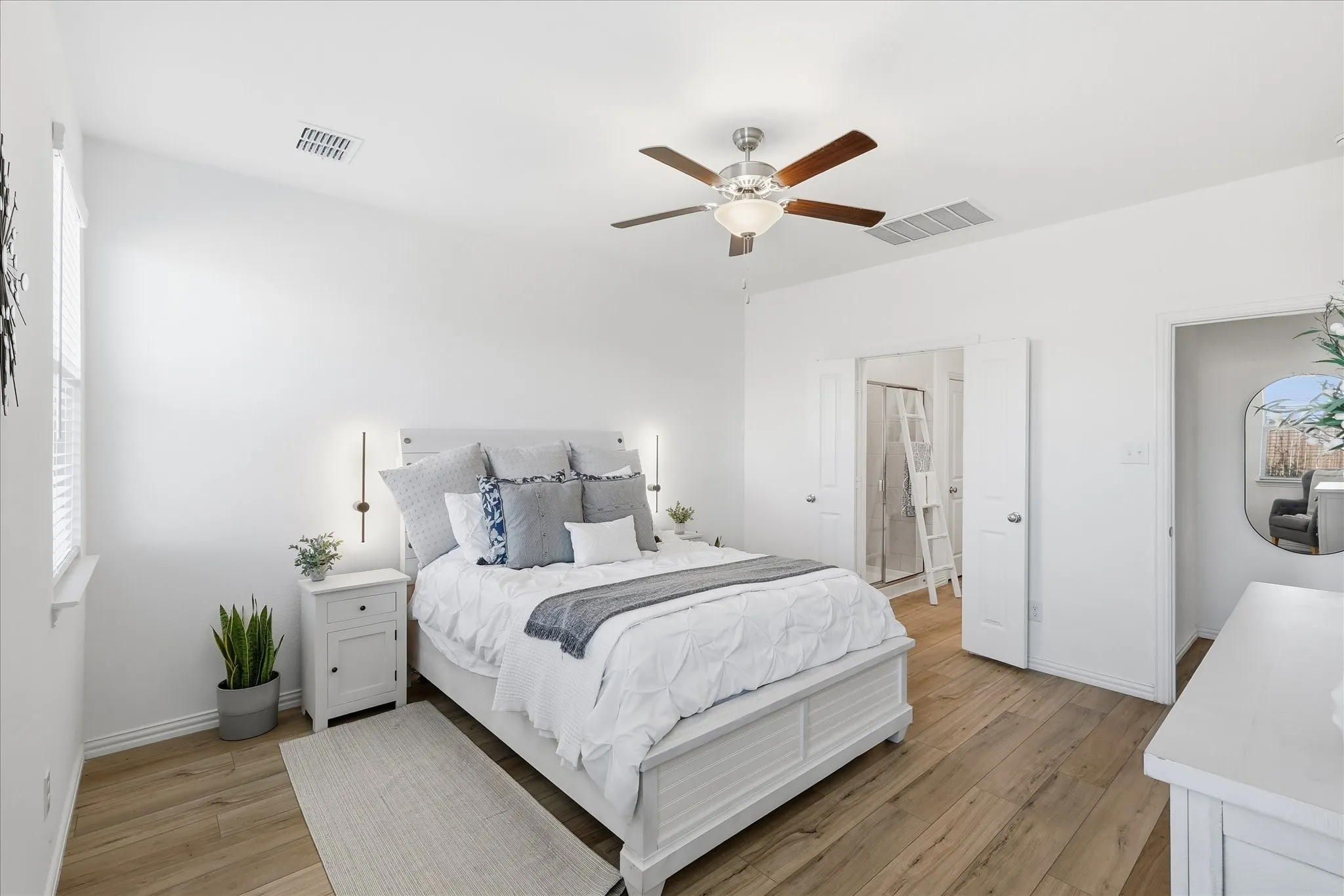 Primary bedroom featuring light LVP floors and ceiling fan.