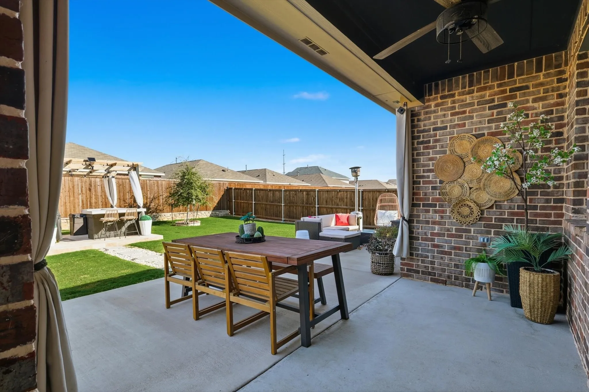 View of fenced backyard from extended patio, featuring an outdoor kitchen prep area, extended patio and lots of seating options in addition to storage.