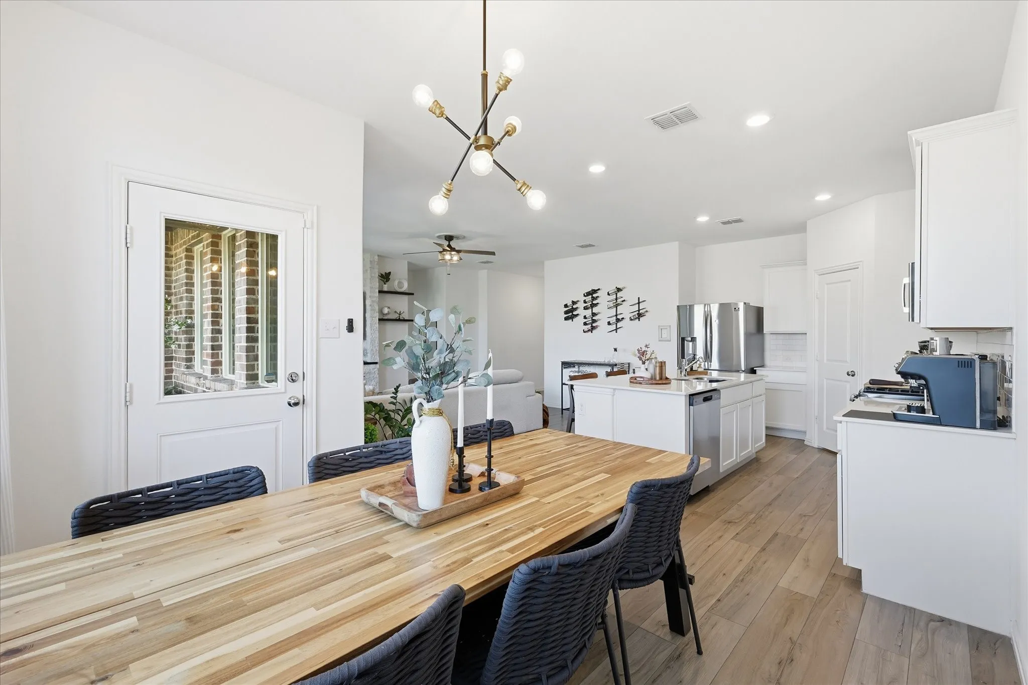 Dining area with a ceiling fan, light LVP flooring, and hanging lights