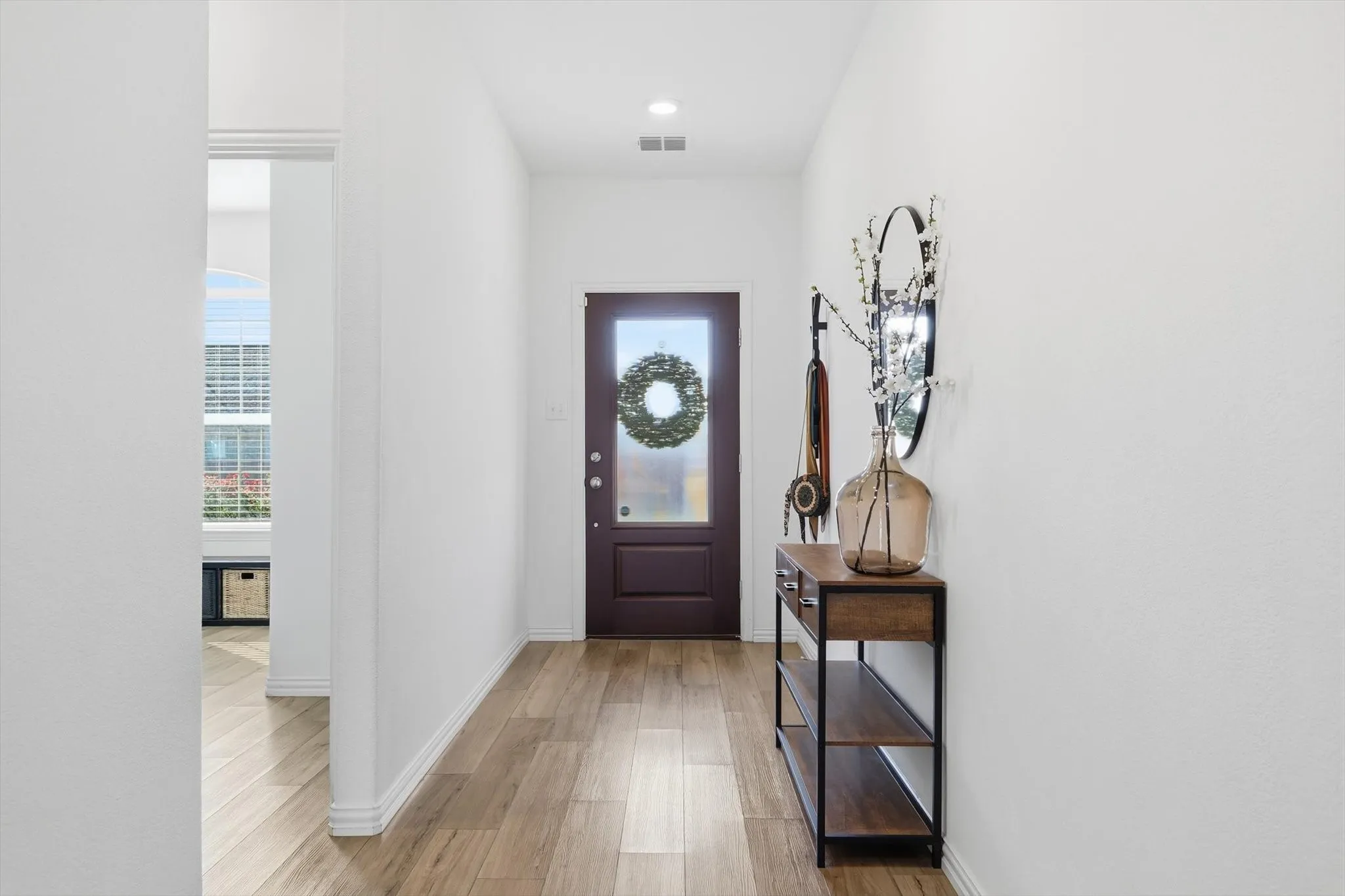 Foyer featuring a stained glass and wood door, high ceilings and light LVP floors.