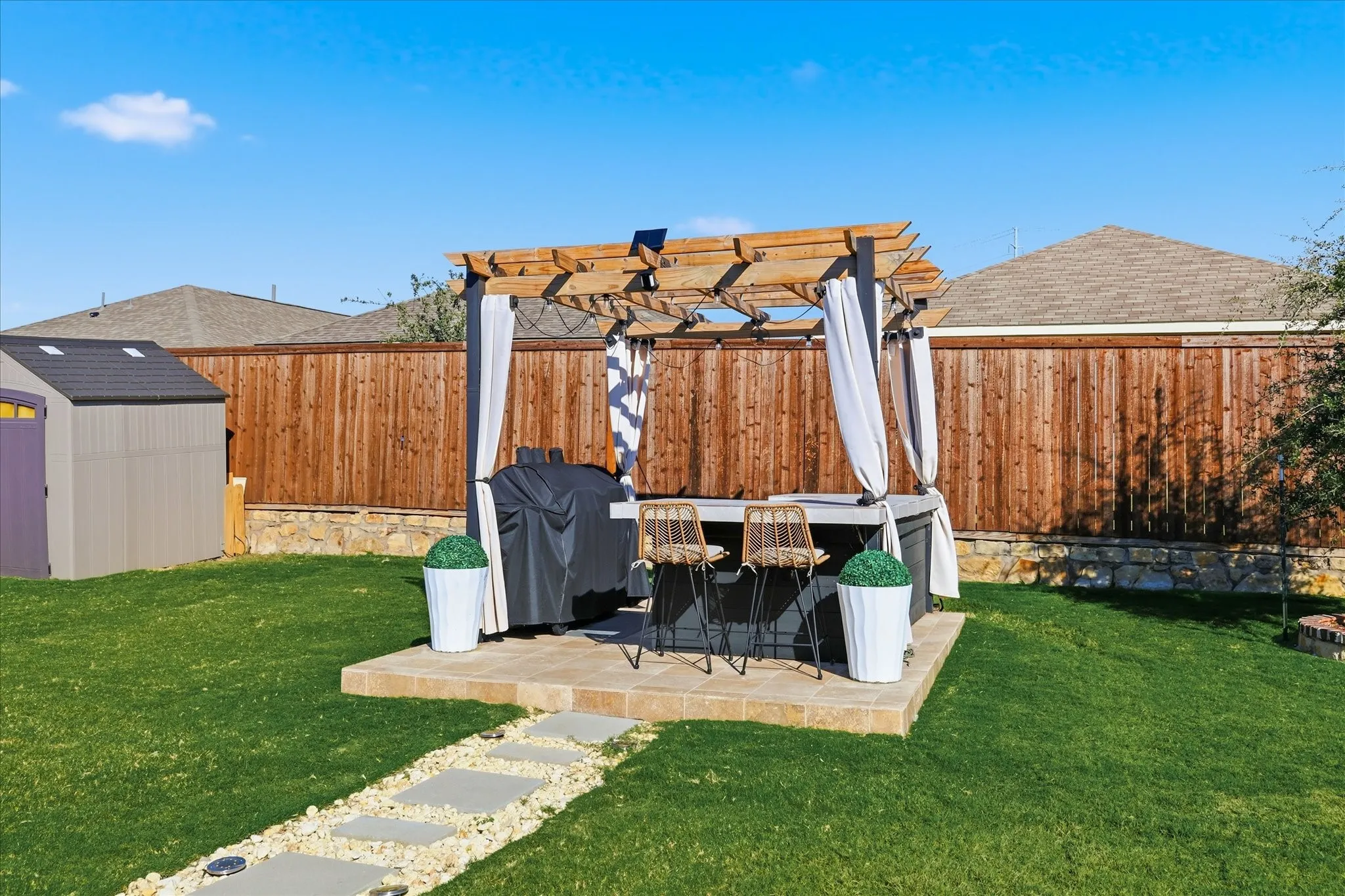 View of fenced backyard, featuring an outdoor kitchen prep area, extended patio and lots of seating options in addition to​​‌​​​​‌​​‌‌​‌‌​​​‌‌​‌​‌​‌​​​‌​​ storage.