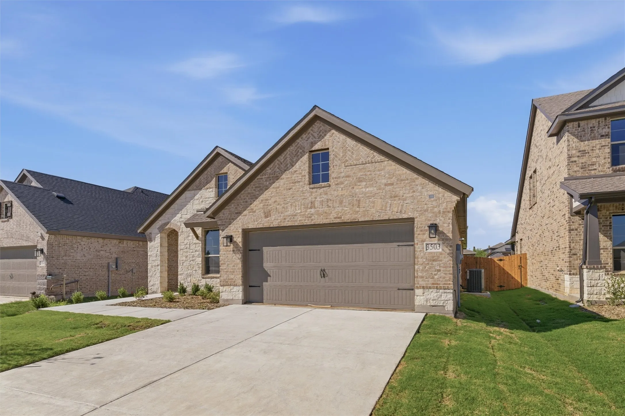 View of front of property with driveway, brick siding, stone siding, and a garage