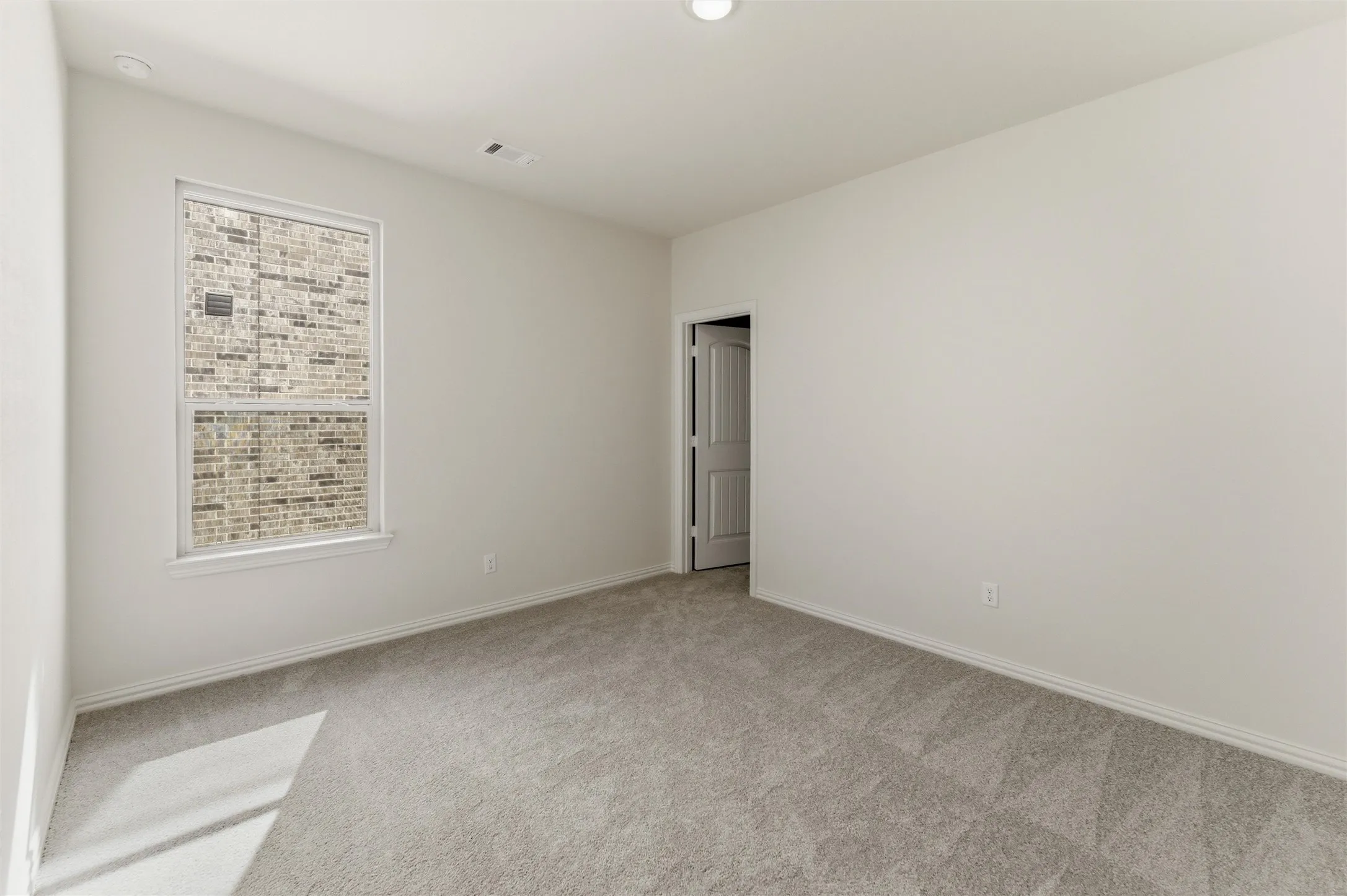 Unfurnished room featuring light carpet and baseboards