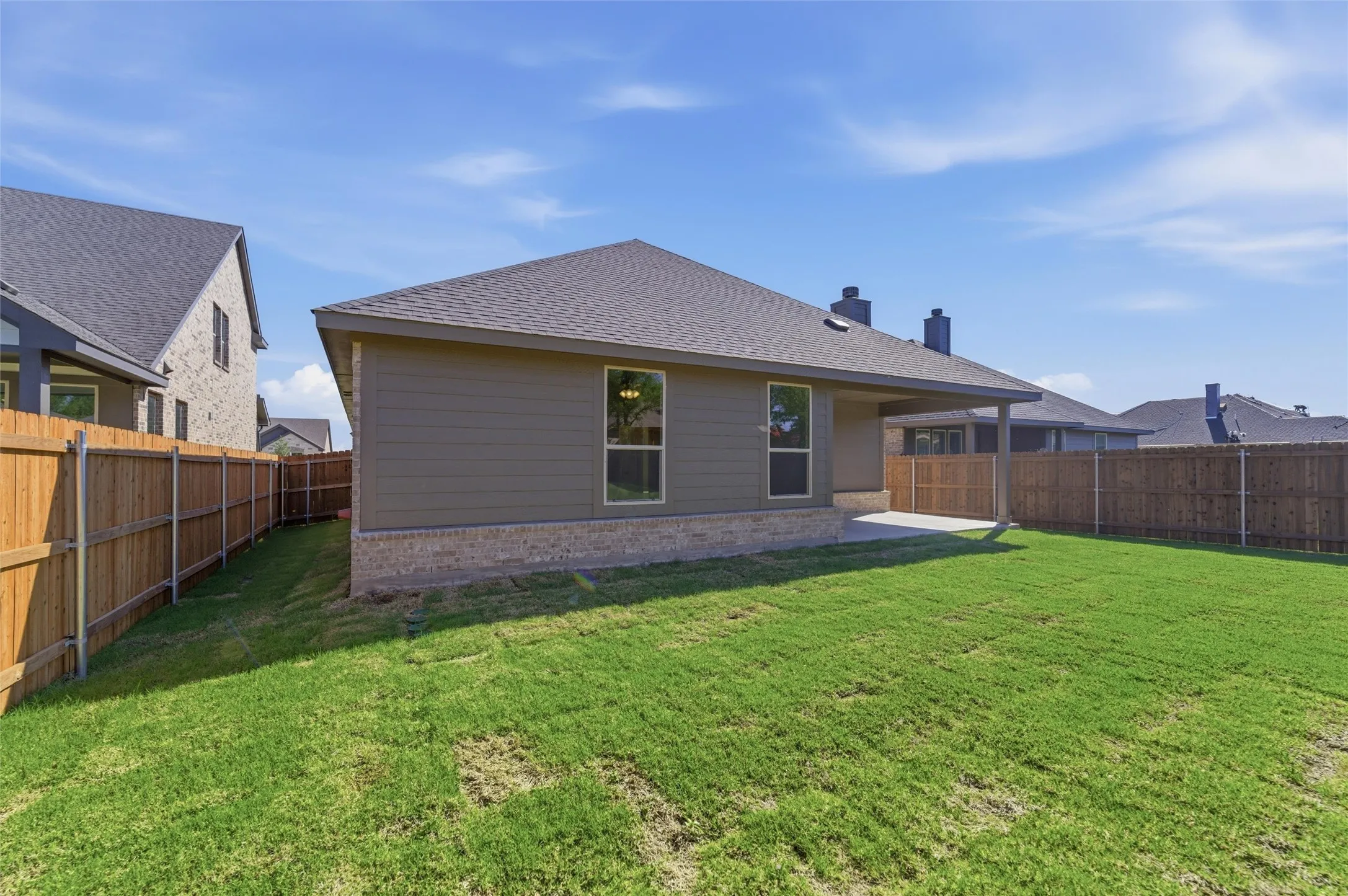 Back of house featuring a patio area, brick siding, a shingled roof, a fenced backyard, and a chimney