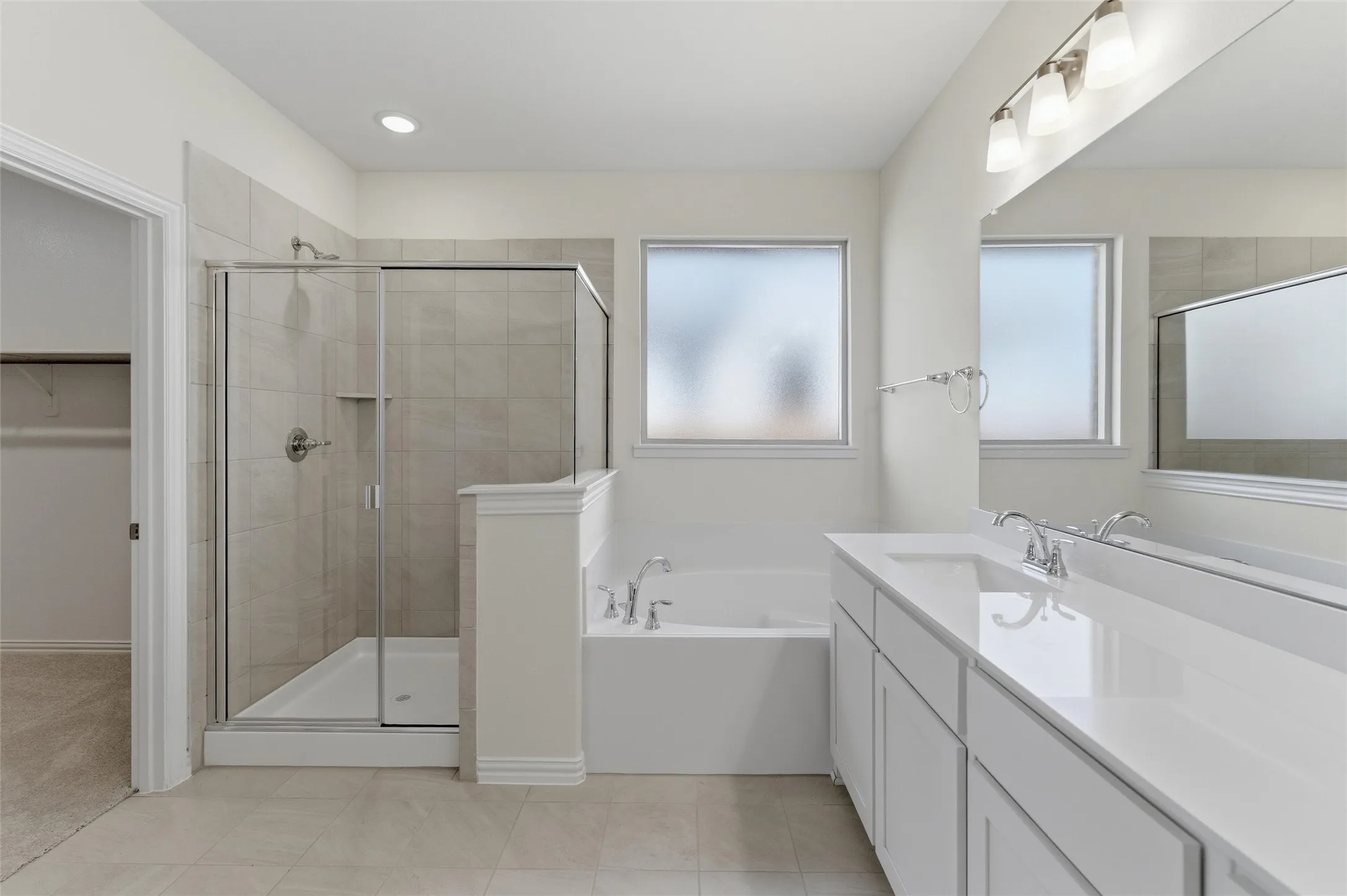 Full bathroom with vanity, a garden tub, a spacious closet, a stall shower, and light tile patterned flooring