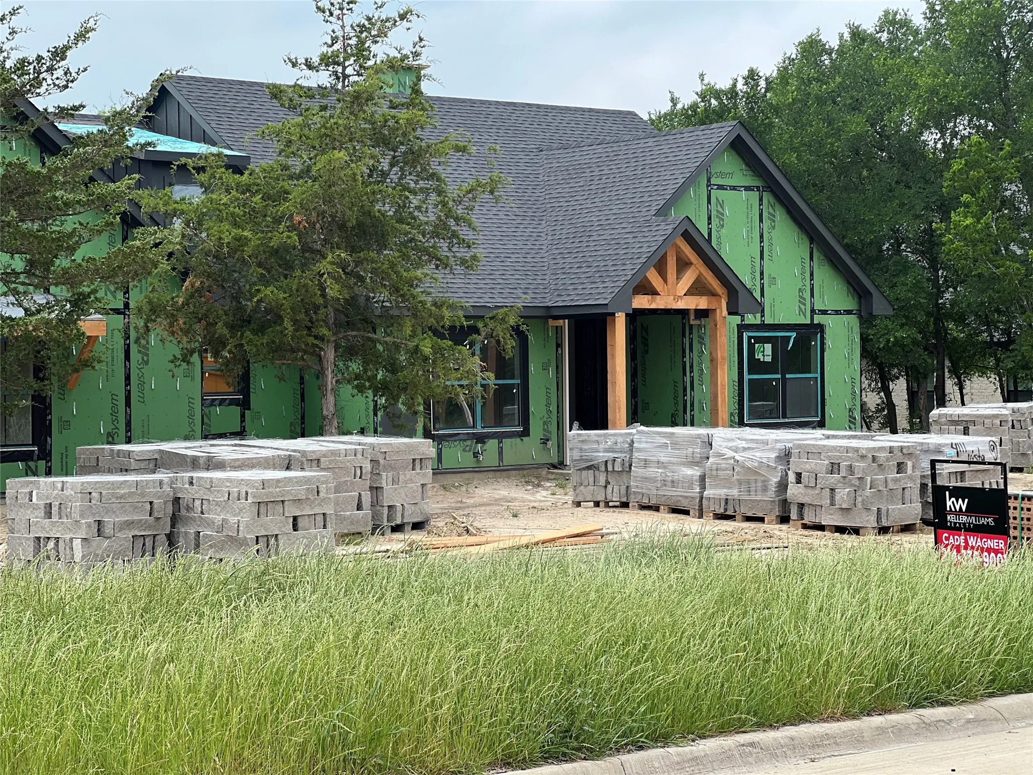 Contemporary style facade featuring a dark shingled roof, black trim accents, and a prominent timber-frame entry