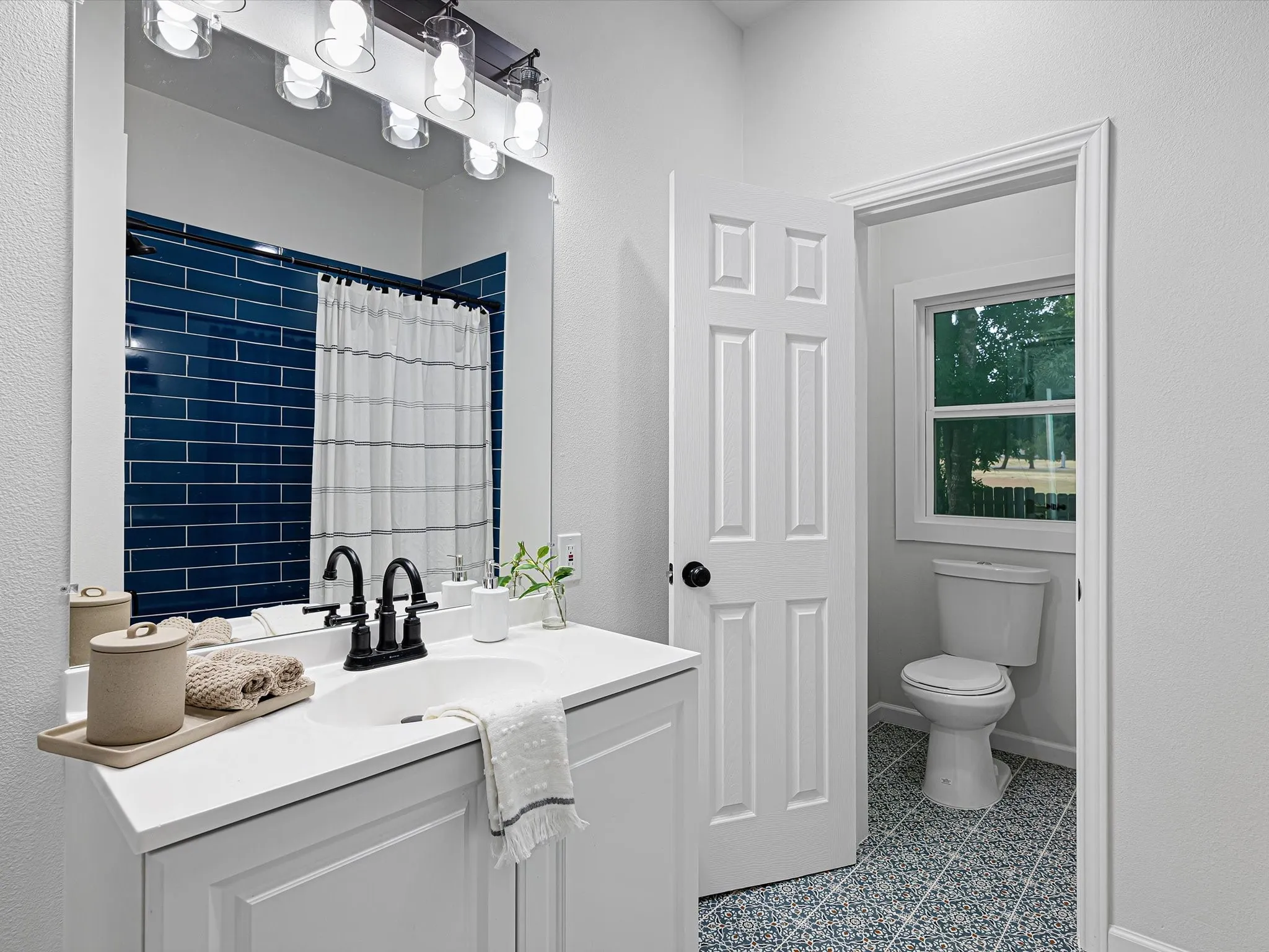 Ensuite primary bathroom is updated featuring cute tile shower, modern tile on the floors, nice lighting, a vanity, etc.